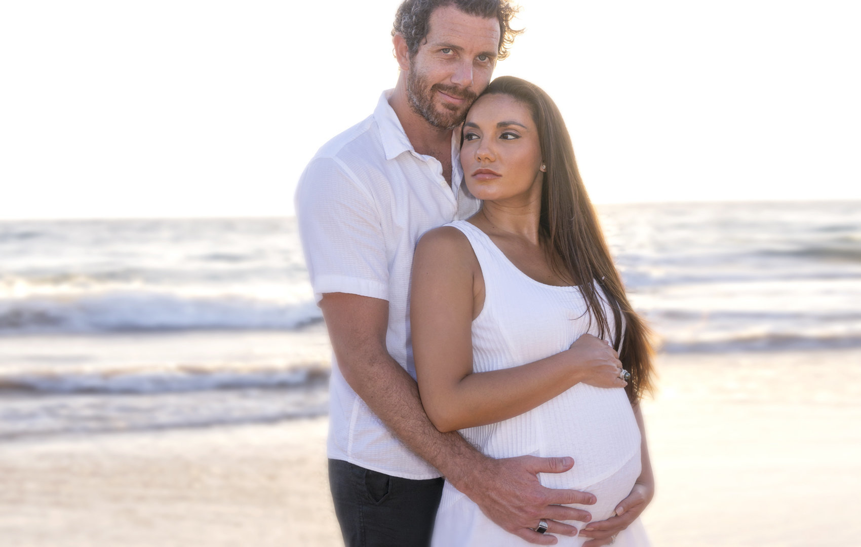 pregnant woman held by her husband on the beaches of Maui.