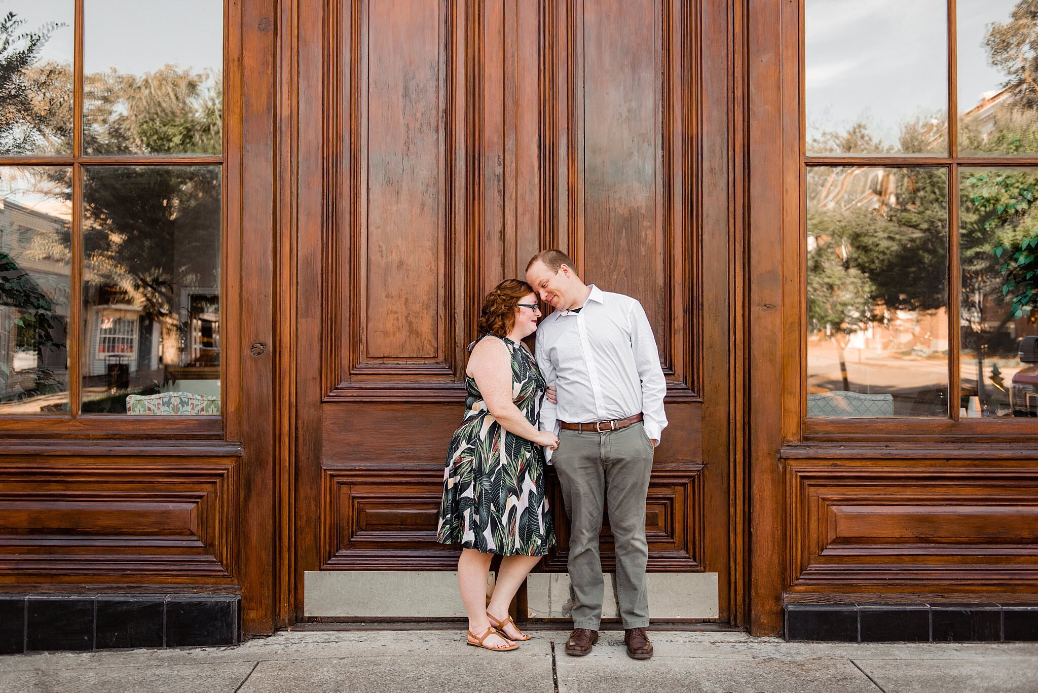Engaged couple standing together in front of oversized wood doors  in downtown Murfreesboro on the square