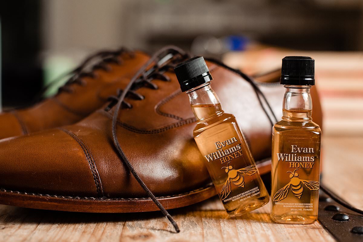 Mini bottles of Jack Daniels Honey shots next to the grooms brown shoes