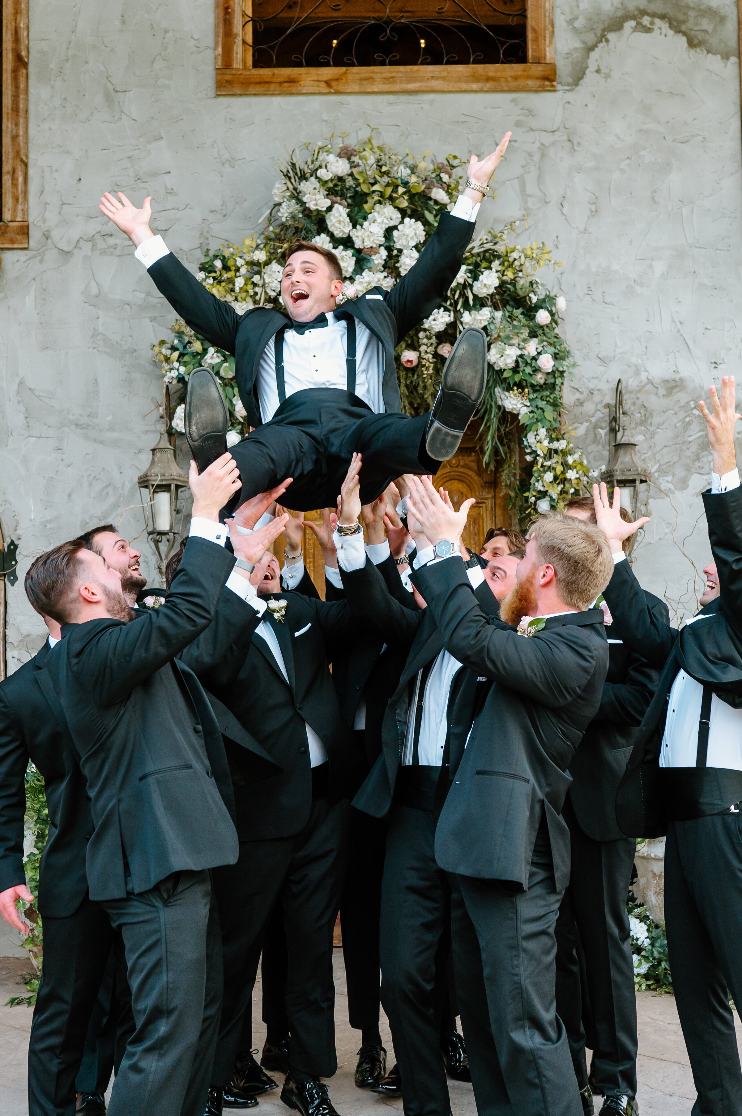 Groomsmen tossing groom into air