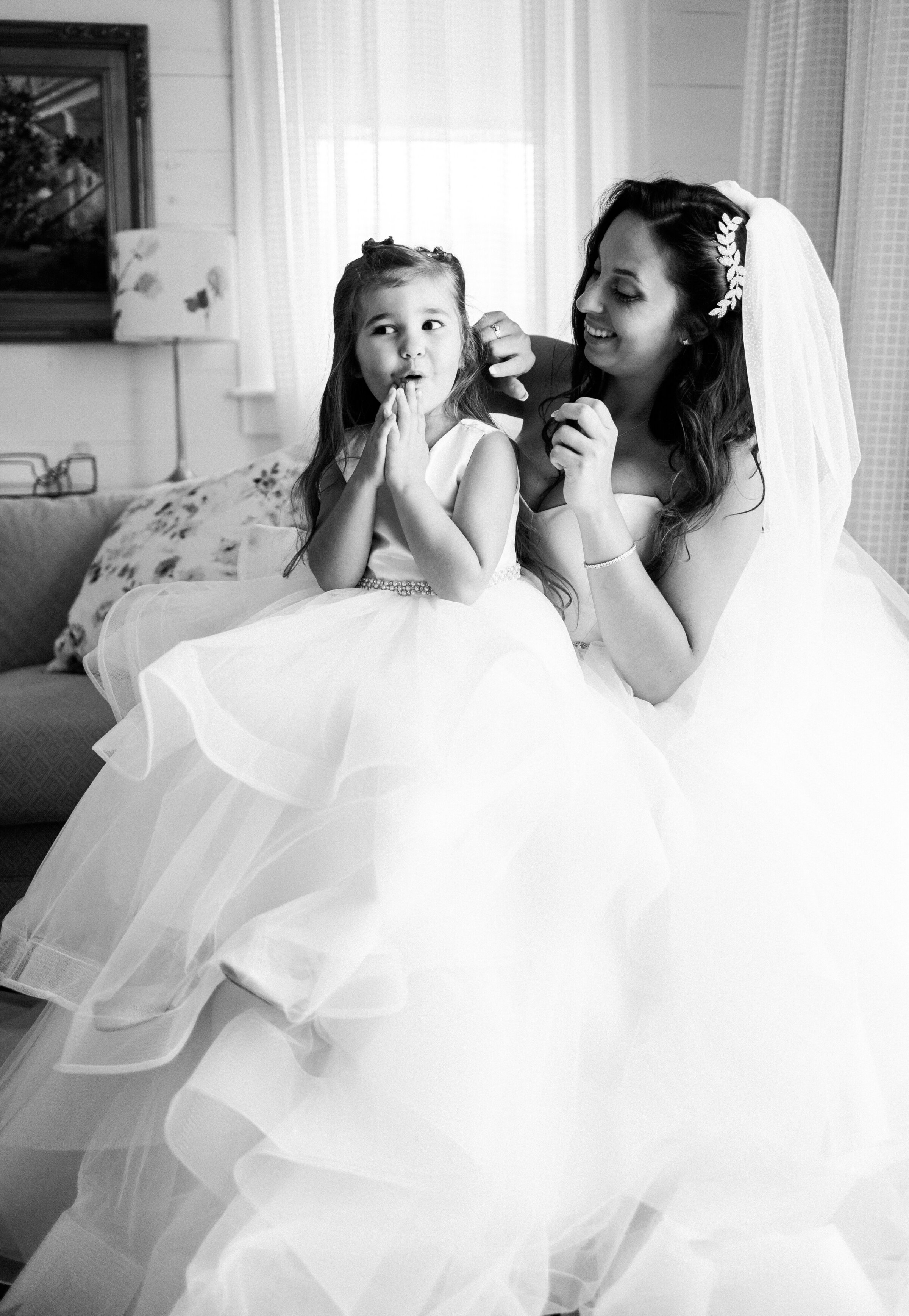 During getting ready, bride puts earrings on her young daughter at The Preserve at Chocura in Tamworth, NH