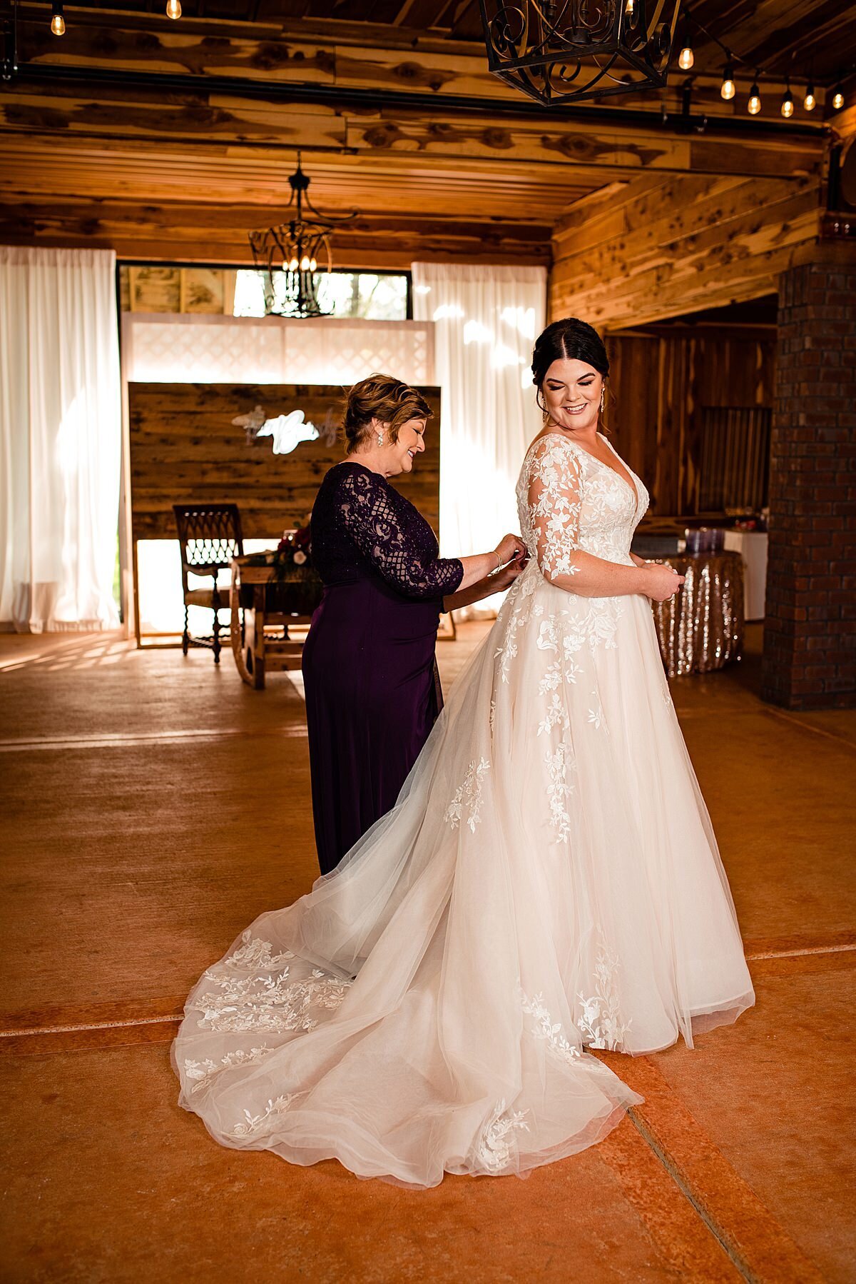 Mother of bride buttoning her daughter's wedding dress at Copper Ridge