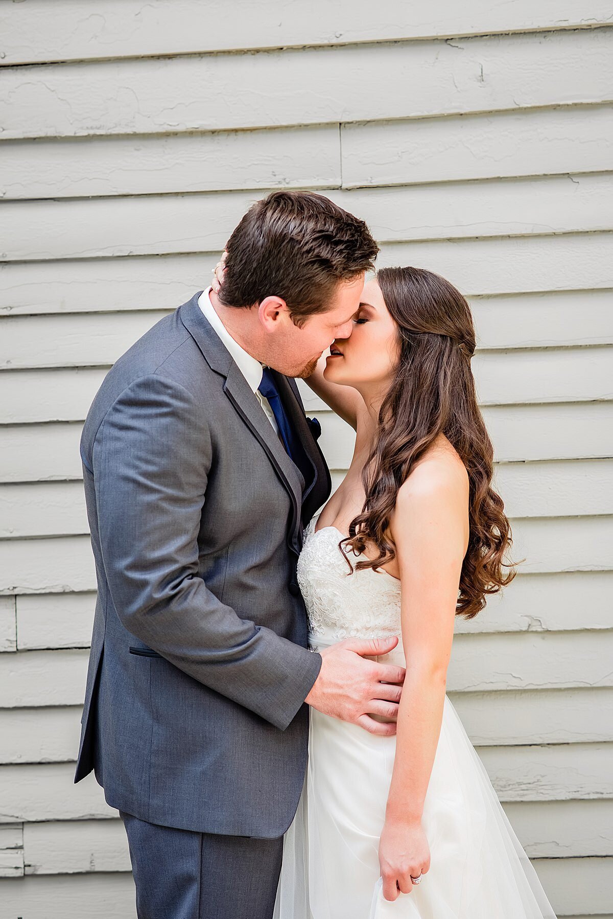 Bride and groom getting ready to share a kiss in front of historic wood barn