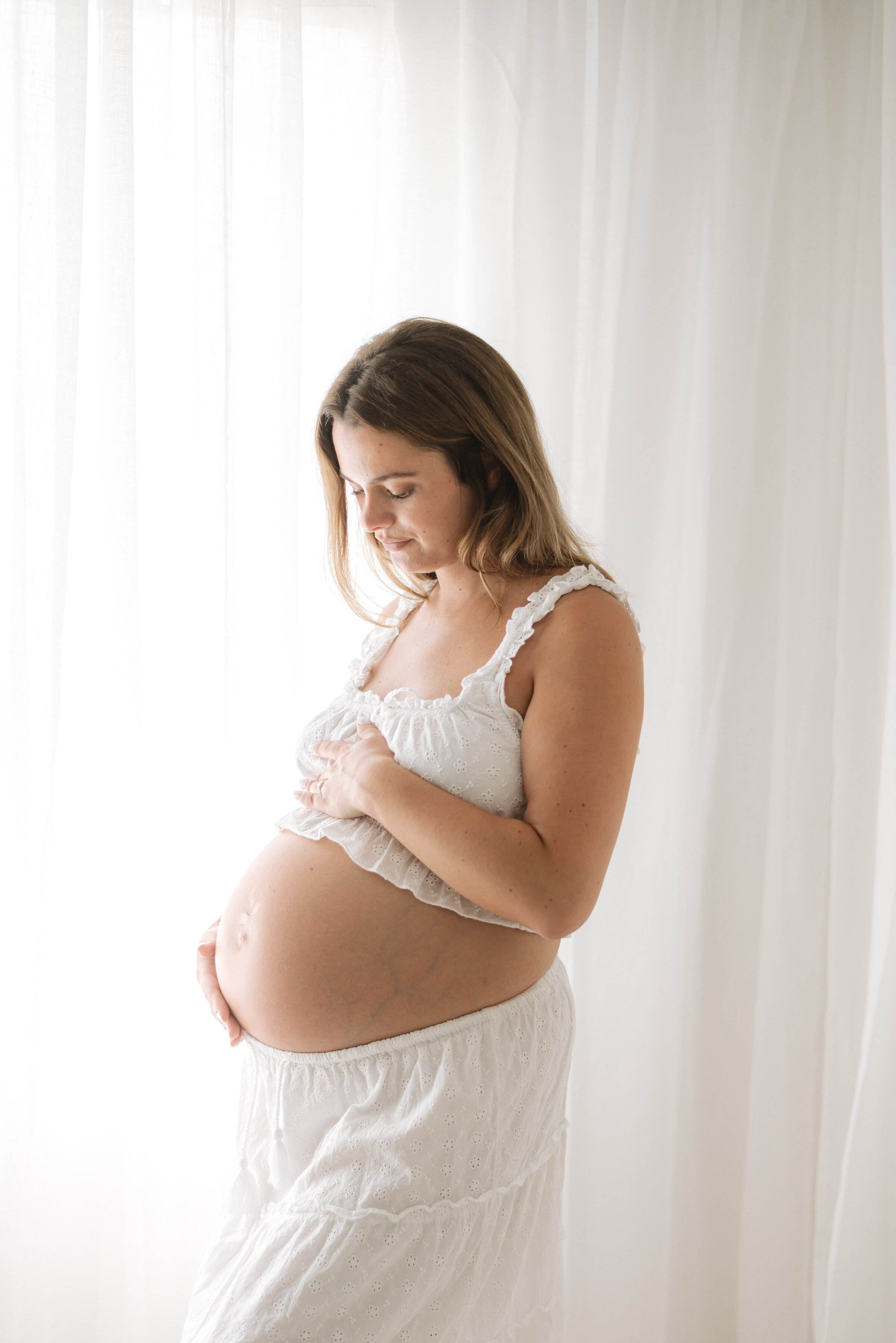 Pregnant women holding her belly smiling at maternity photoshoot in Billingshurst