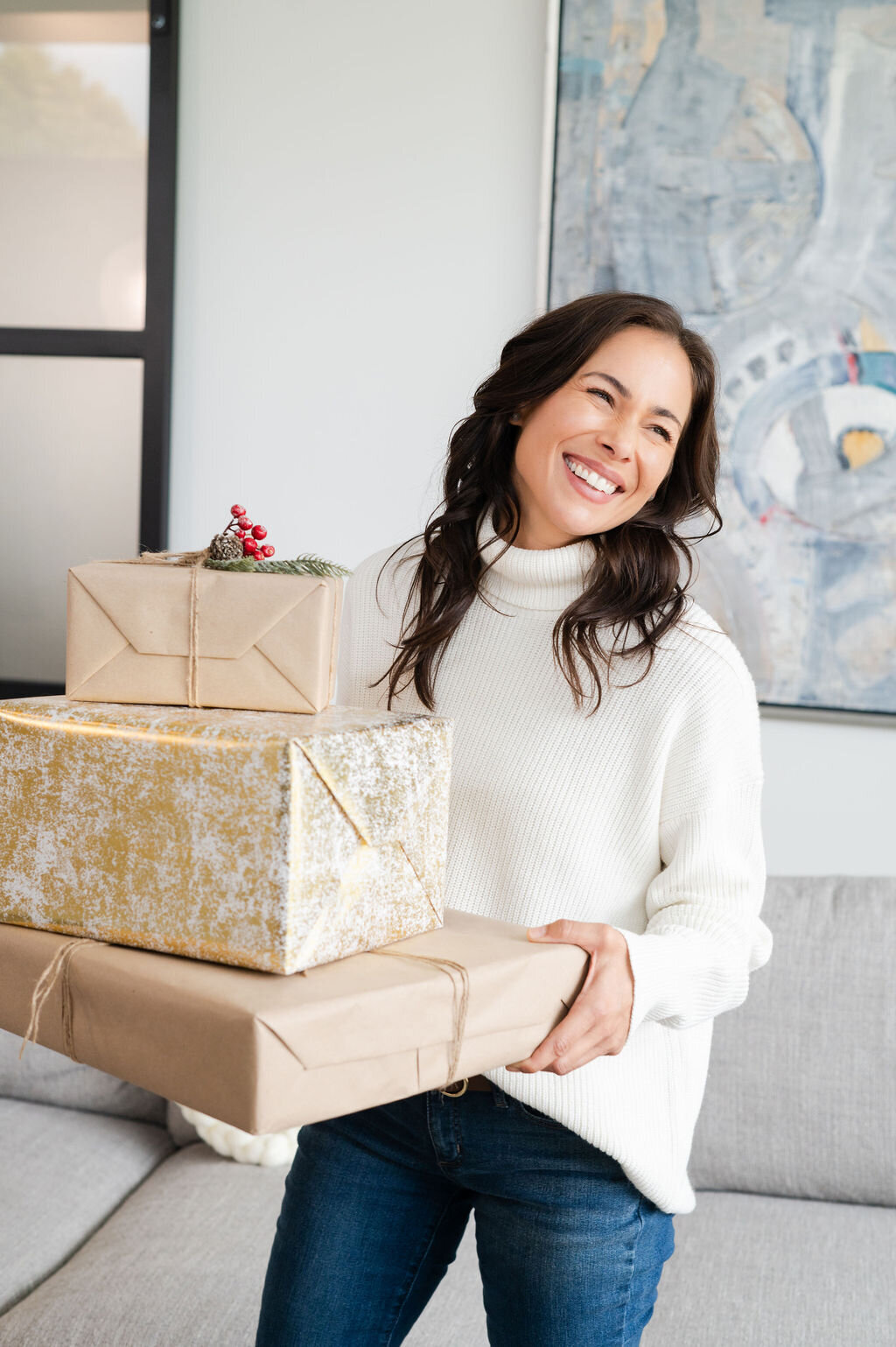Model smiling off camera and carrying a stack of gifts