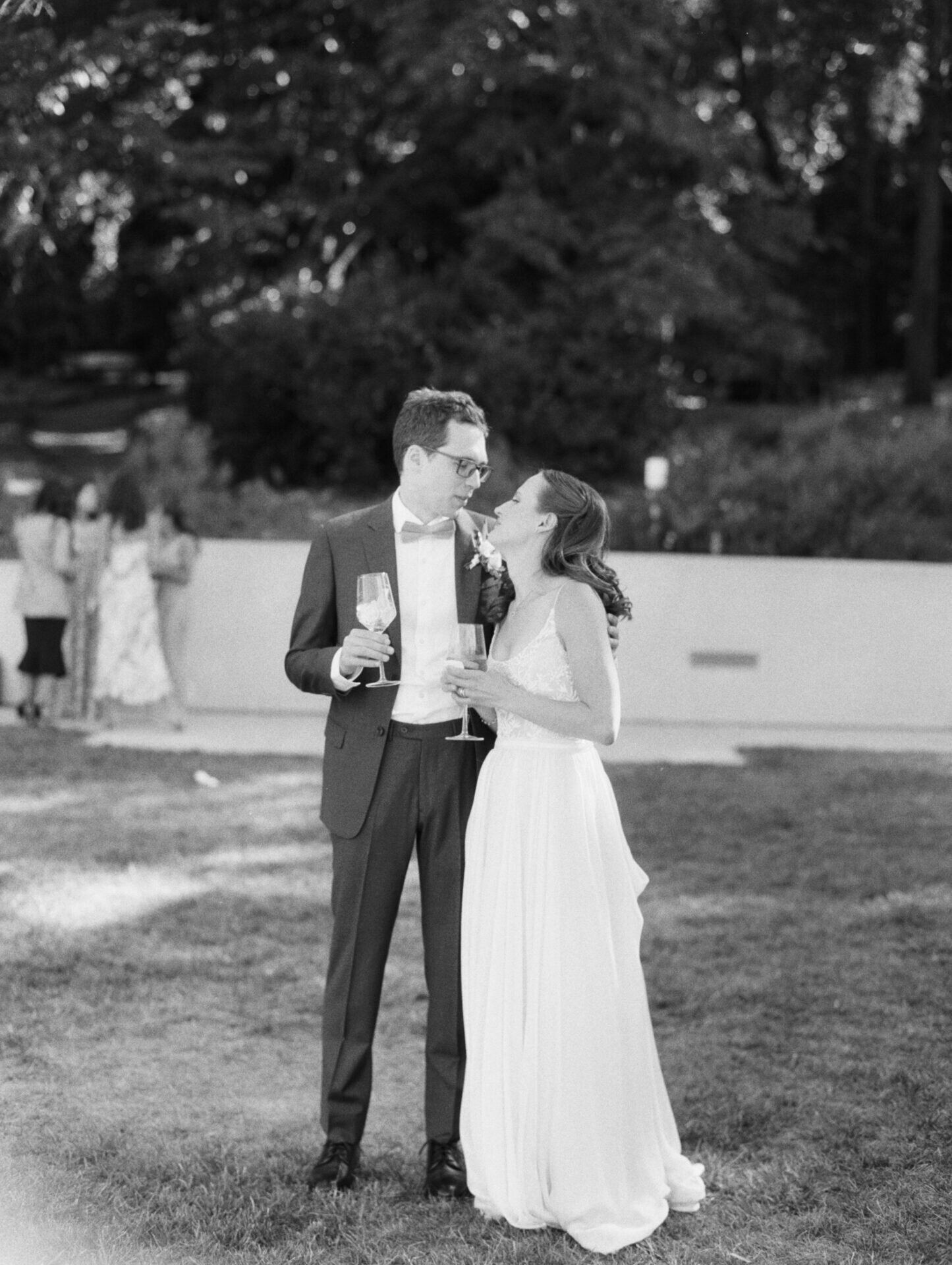black and white film candid photo of bride and groom at cocktail hour outside