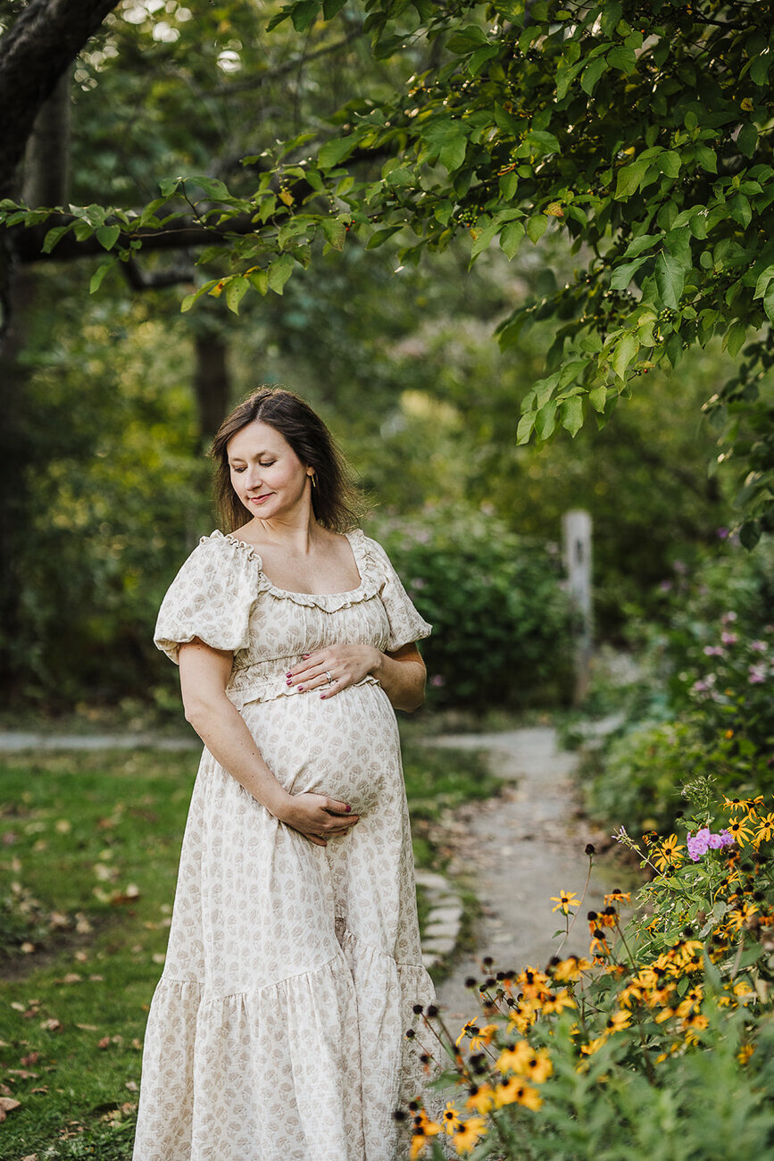 mom in cream dress poses for maternity photos in boston arboretum