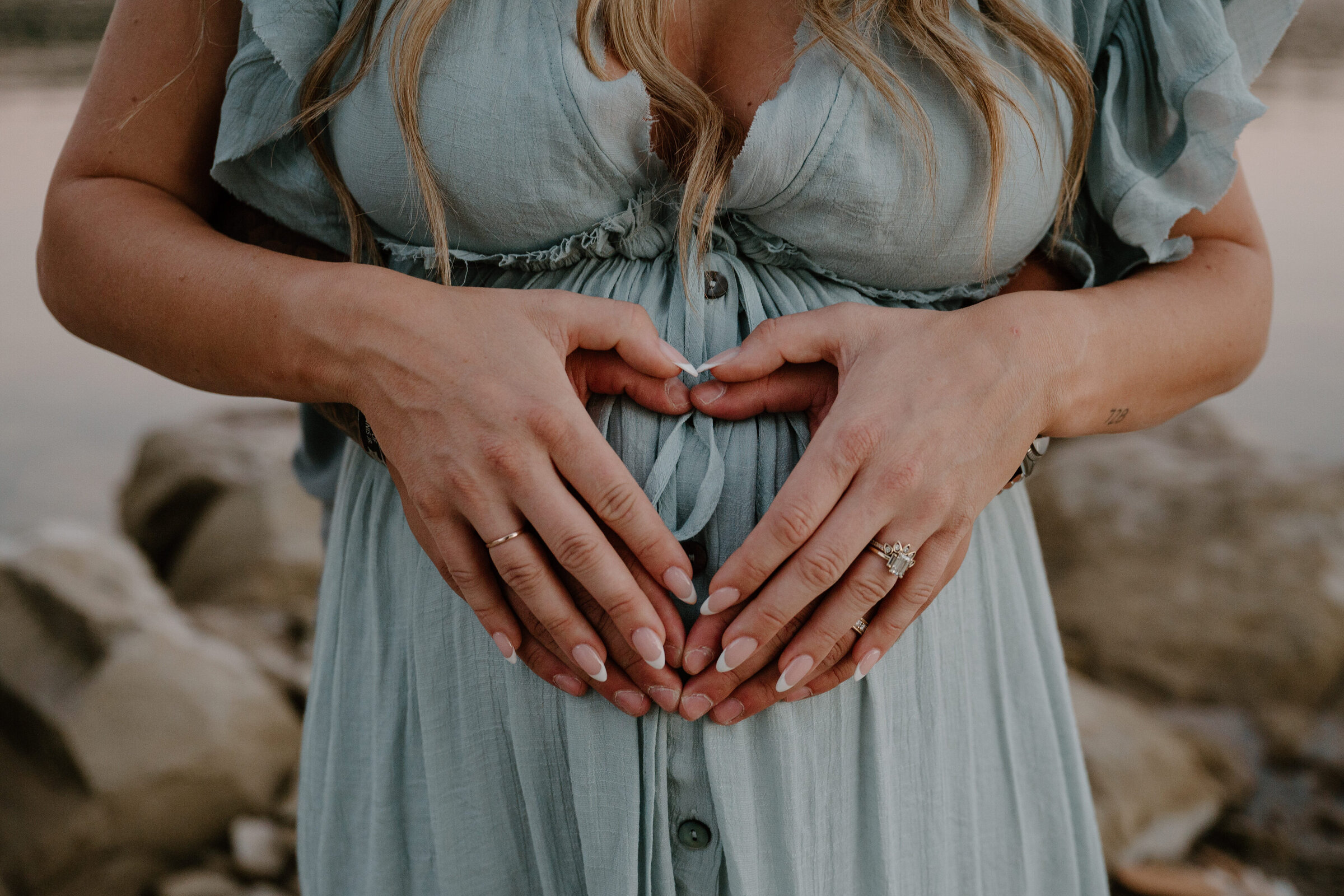 Expecting parents’ hands resting on pregnant belly during an outdoor maternity shoot