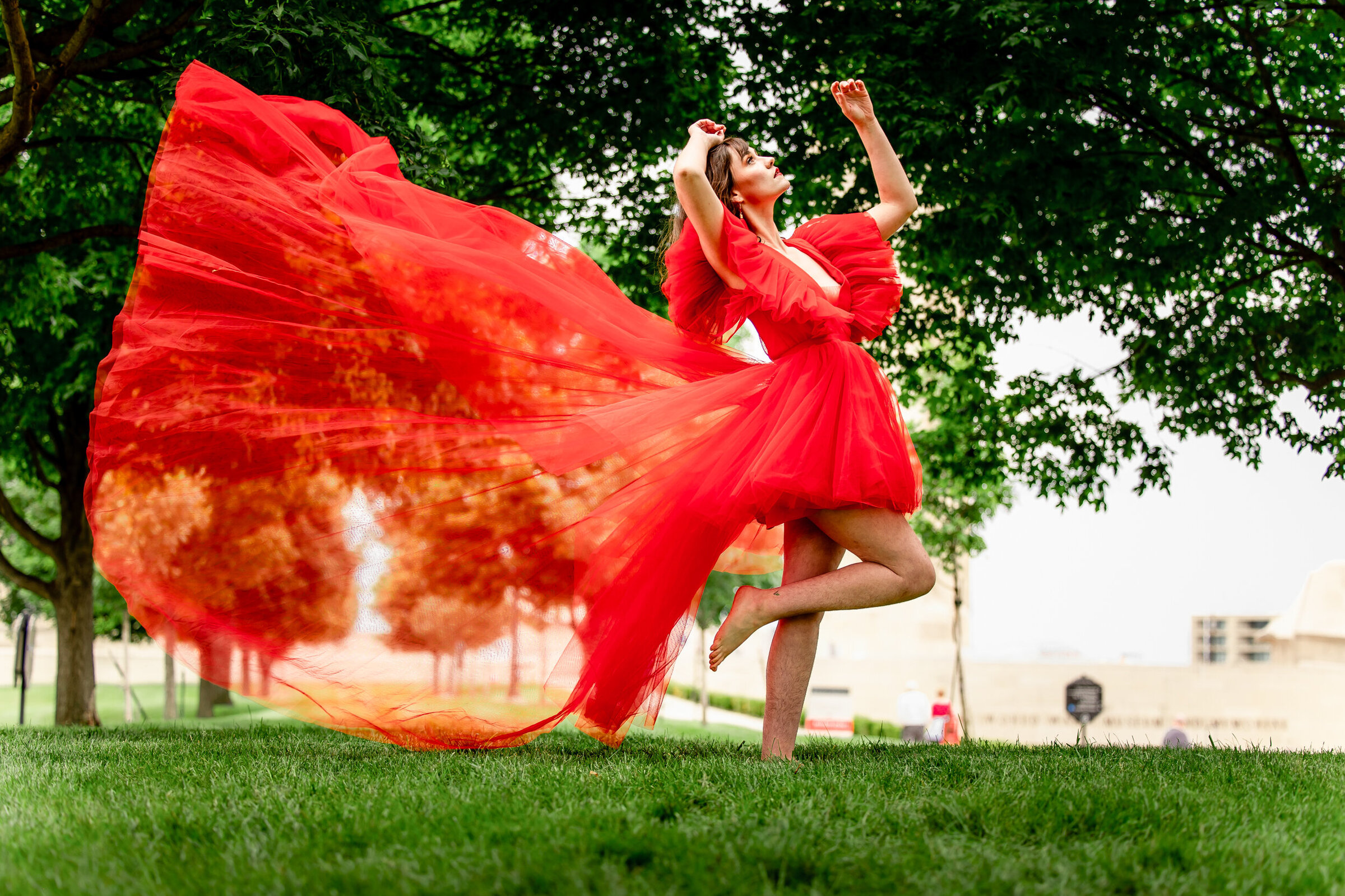 Nikki in a red fly dress with hands over her head and train of dress flying in the wind in kansas city mo
