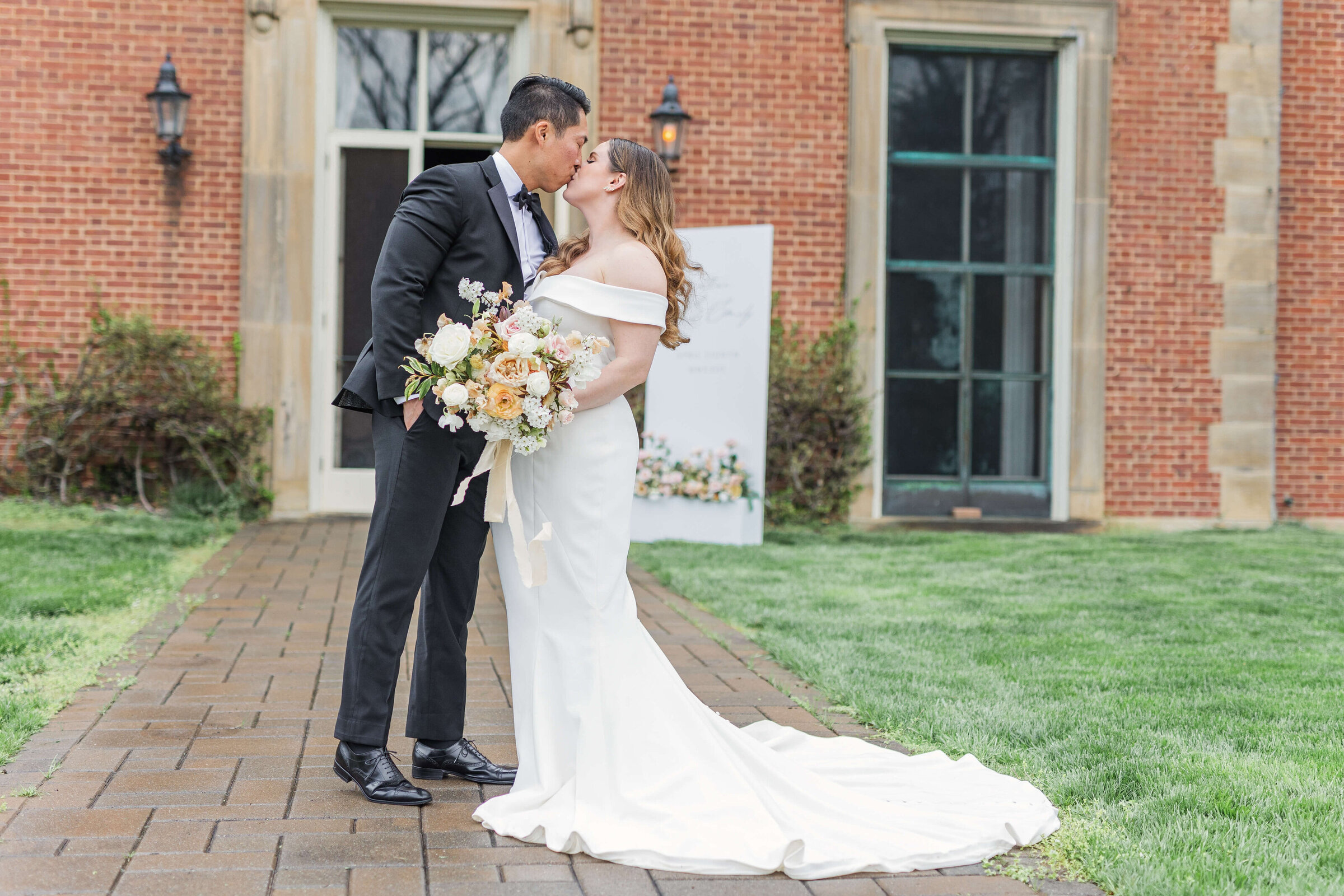 A bride and groom kiss on the grass at Peterloon Estates