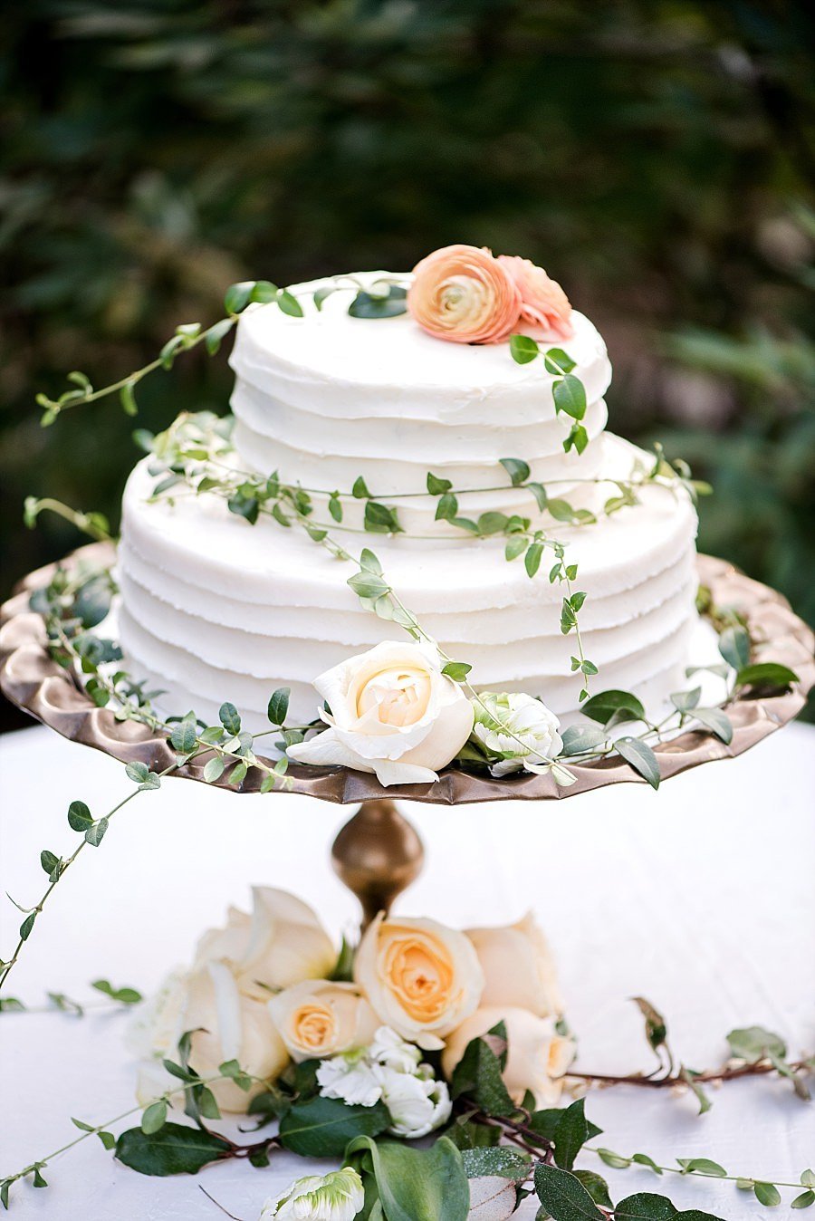 Two tier short cake with orange and ivory flowers and small natural ivy