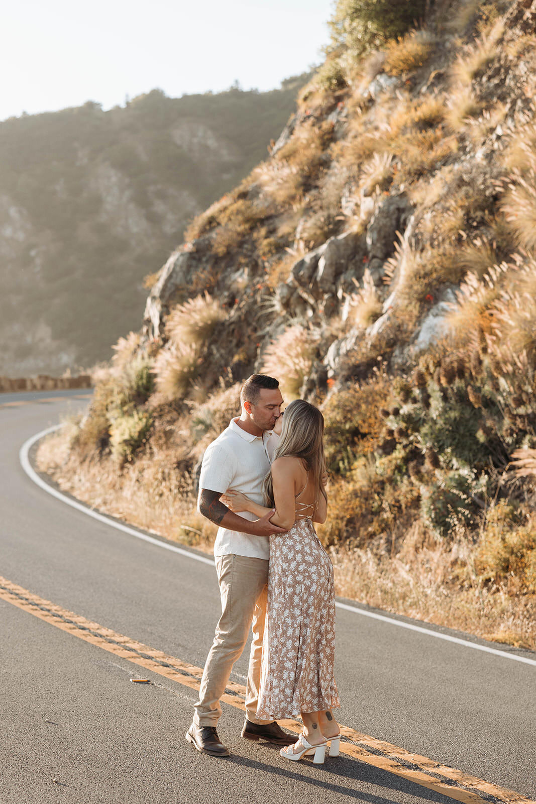 Engaged couple embracing on a winding coastal road