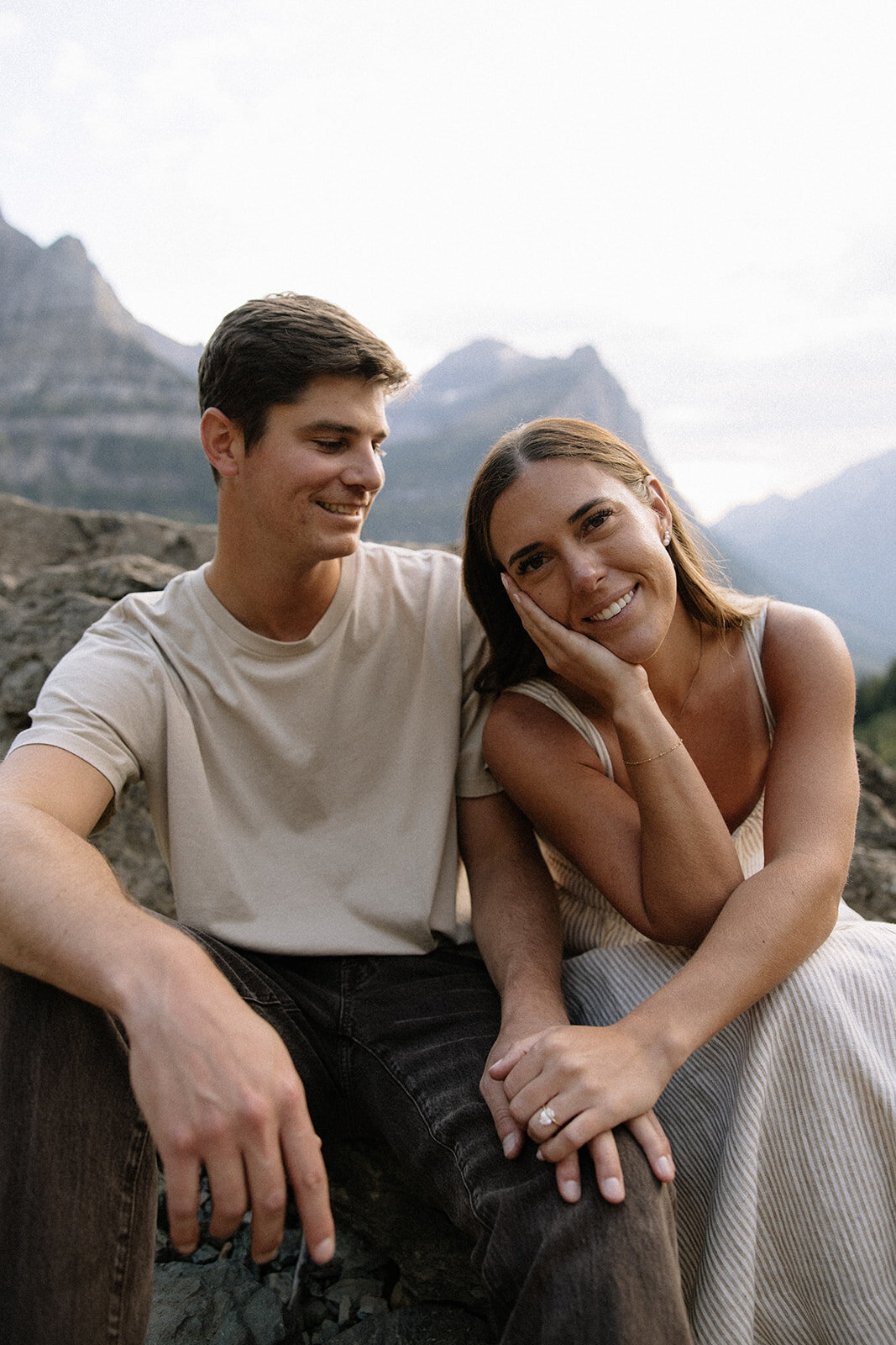 couple sitting on a rock and smiling in glacier national park