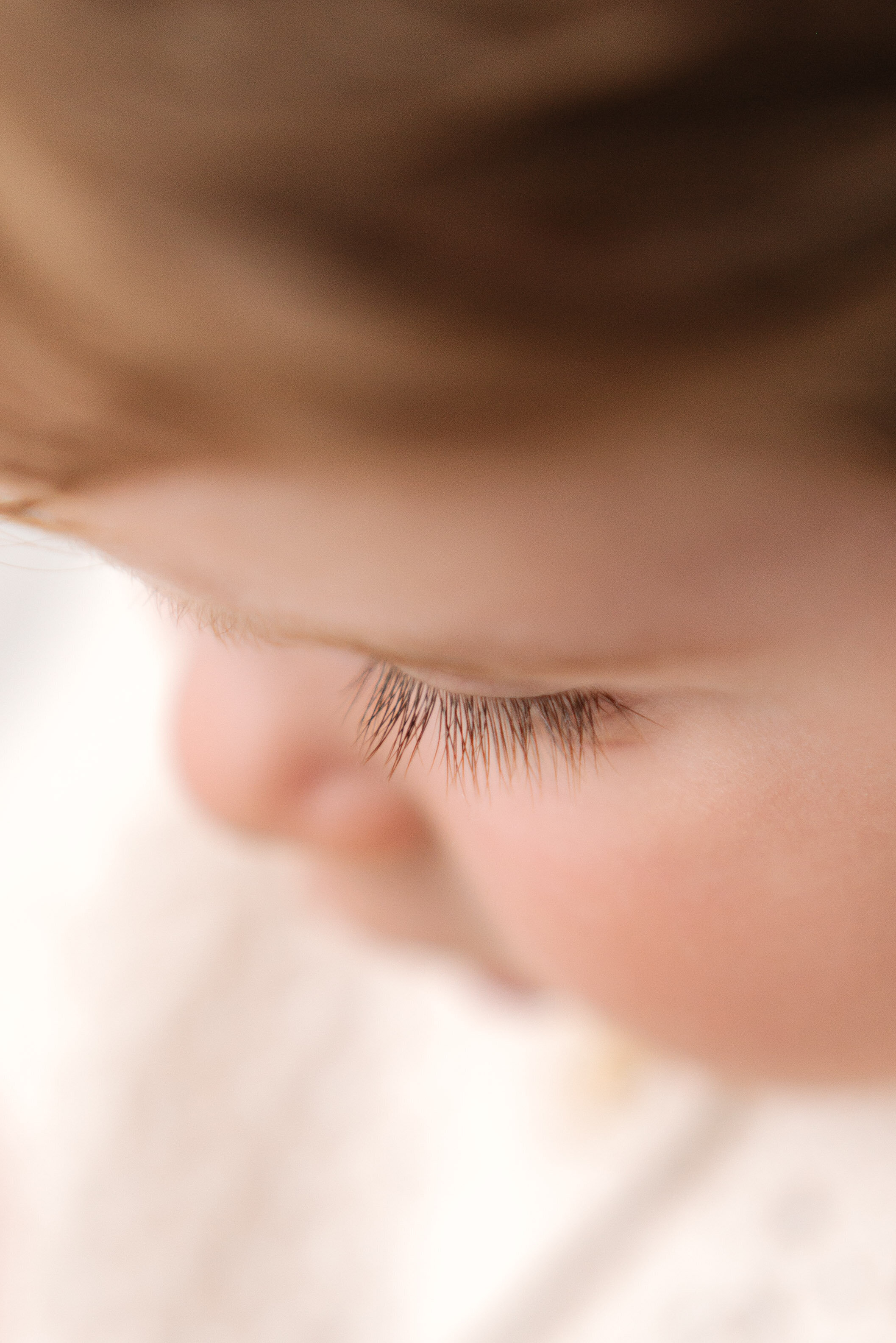 One year old boy looking down with long eye lashes in milestone photoshoot in Billingshurst