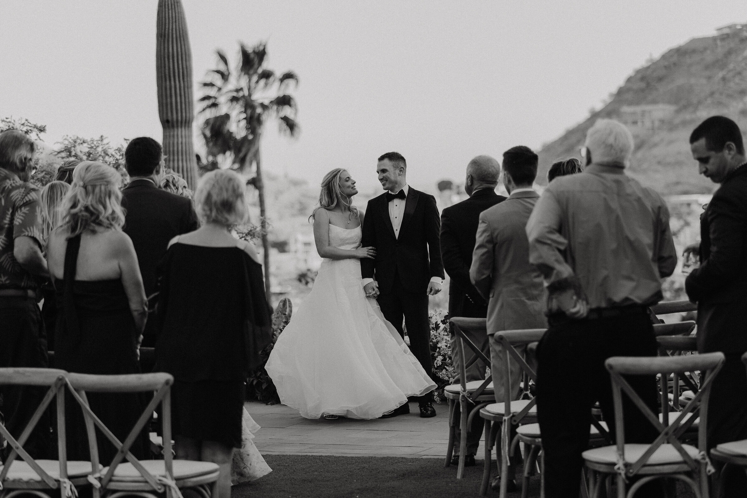 black and whitew photo of a couple standing at the end of the aisle shortly after getting married
