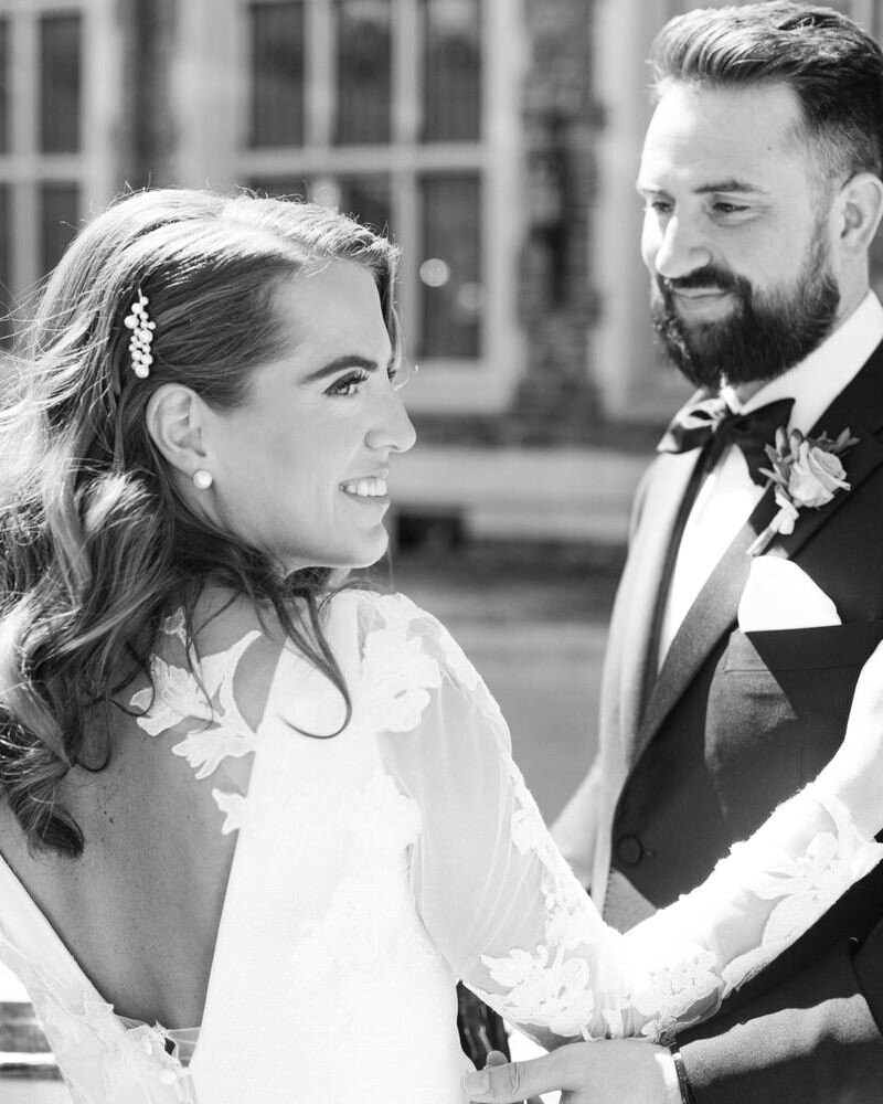 This elegant image captures the bride smiling to her right as the groom holds her close outside the VIP entrance of the Banff Springs Hotel. The couple, glowing with happiness, prepares to step into a Rolls Royce luxury car, setting the stage for their next unforgettable moment.