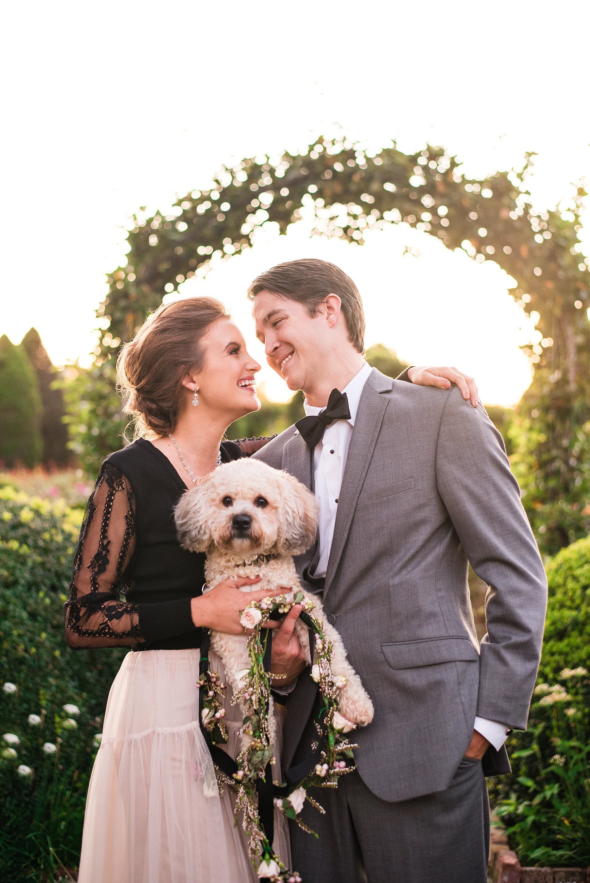 Styled photoshoot of couple standing in the gardens at Carnton Plantation holding their dog who has a flower leash