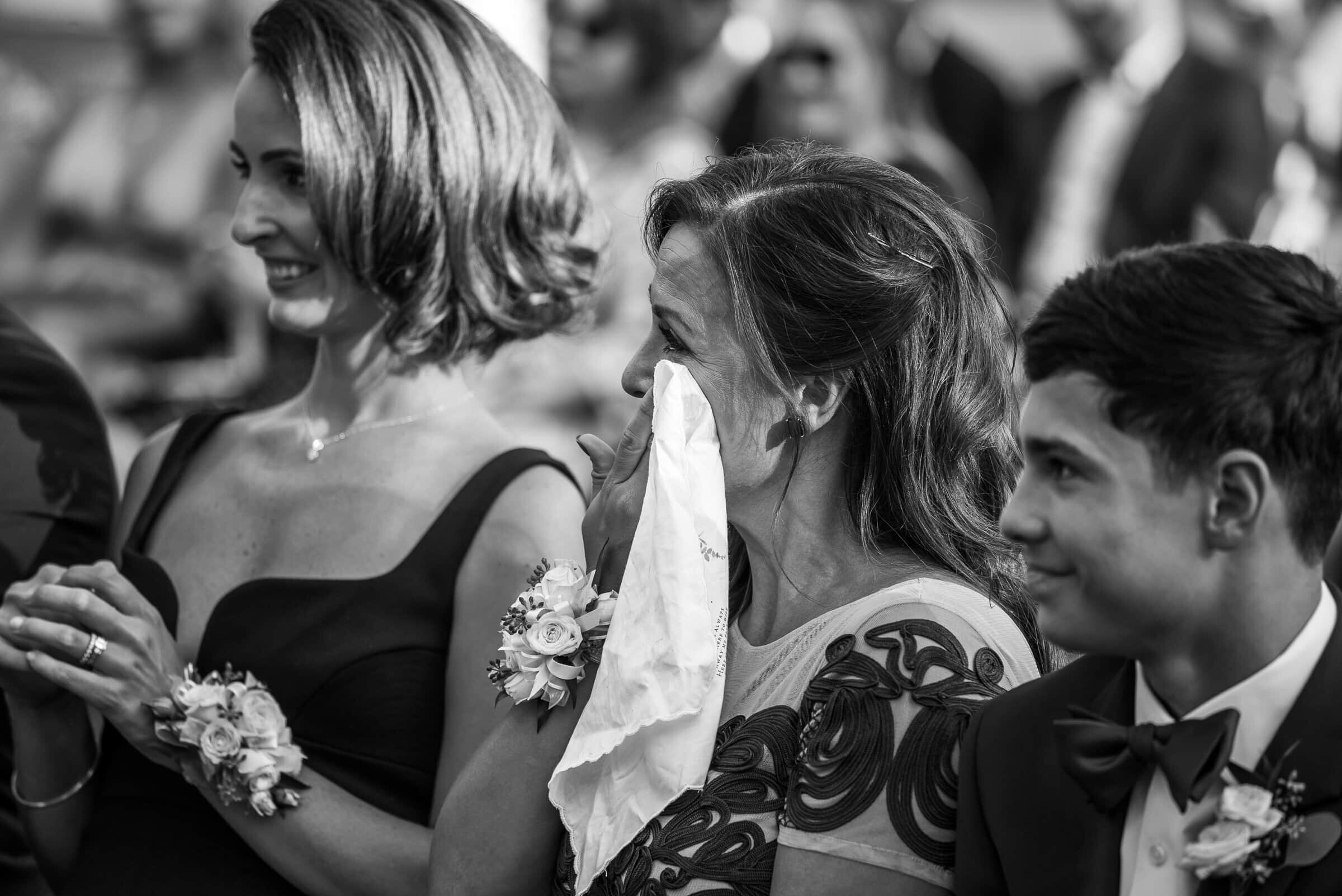 mother of the bride wiping tears while watching her daughter saying her wedding vows.