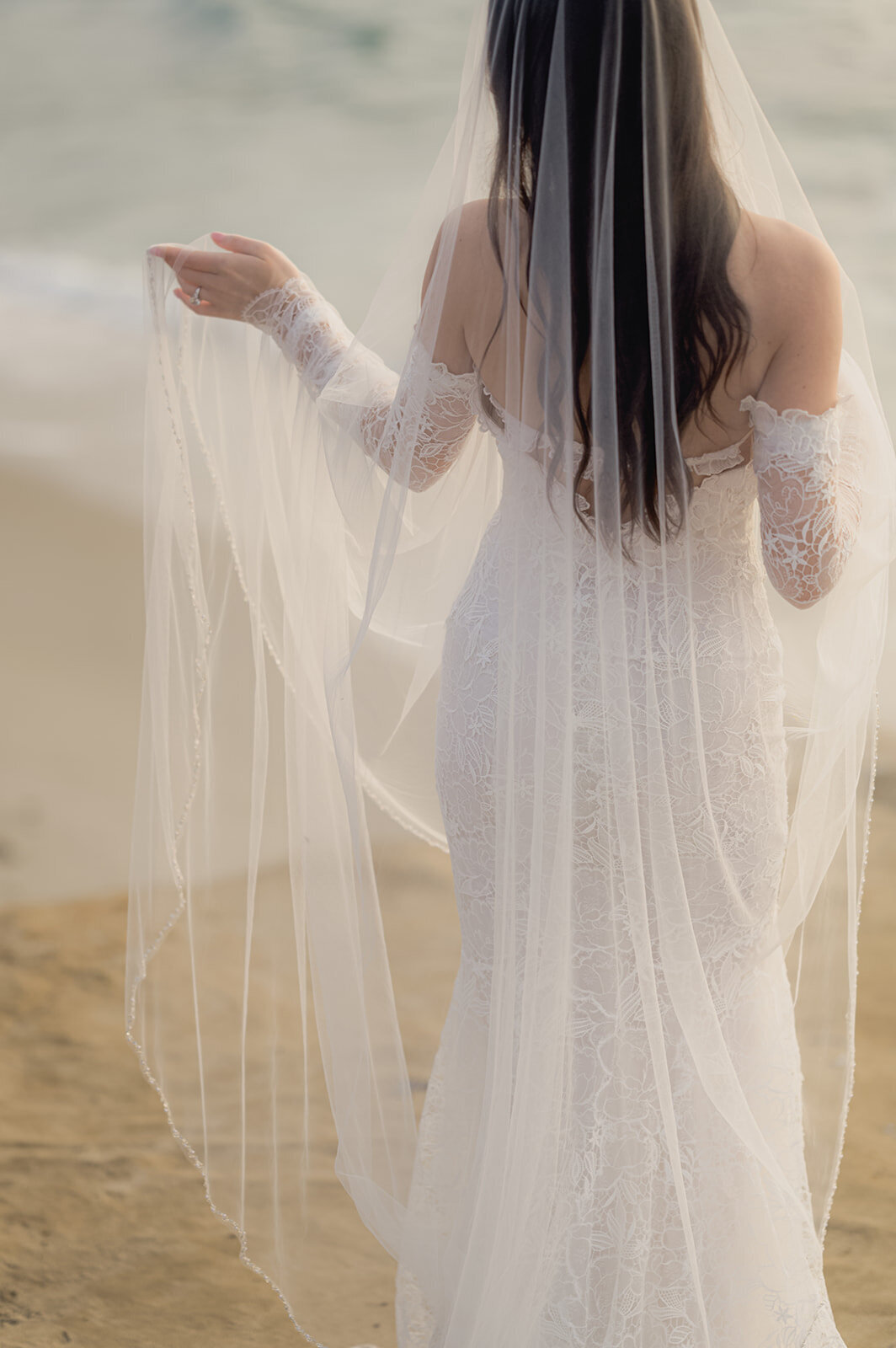 bridal portrait of a bride with a viel overlooking the water at sunset