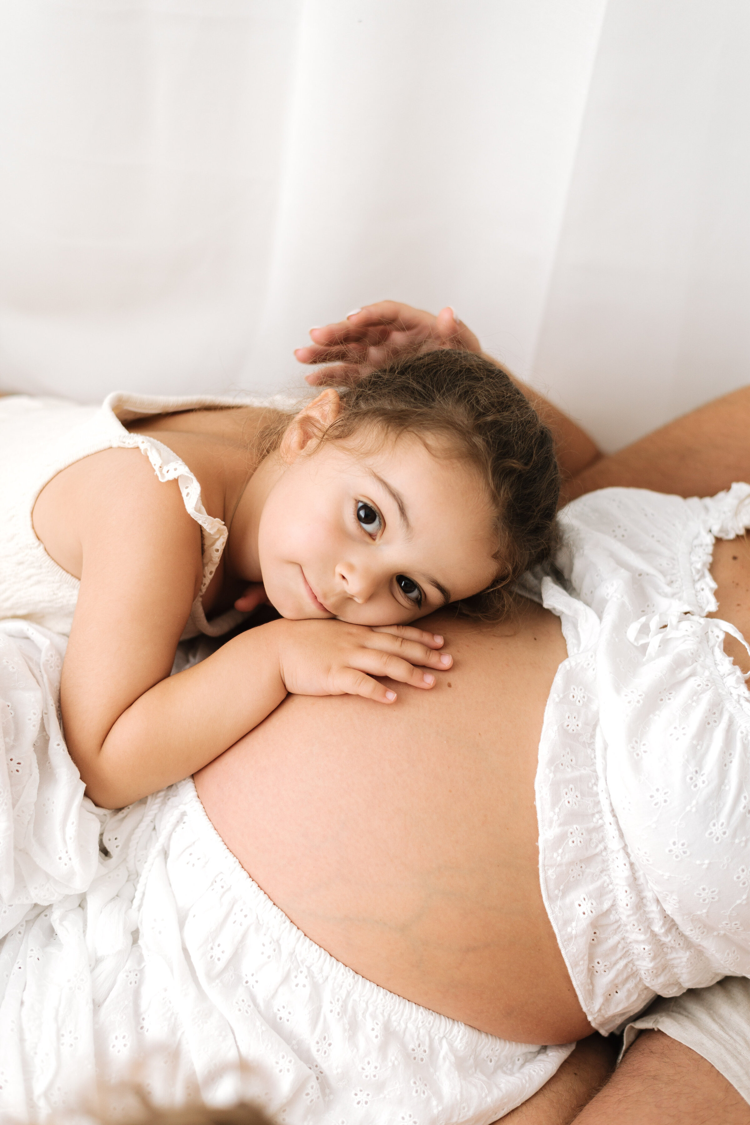 Little girl cuddling her mums pregnant belly at Billingshurst maternity photoshoot