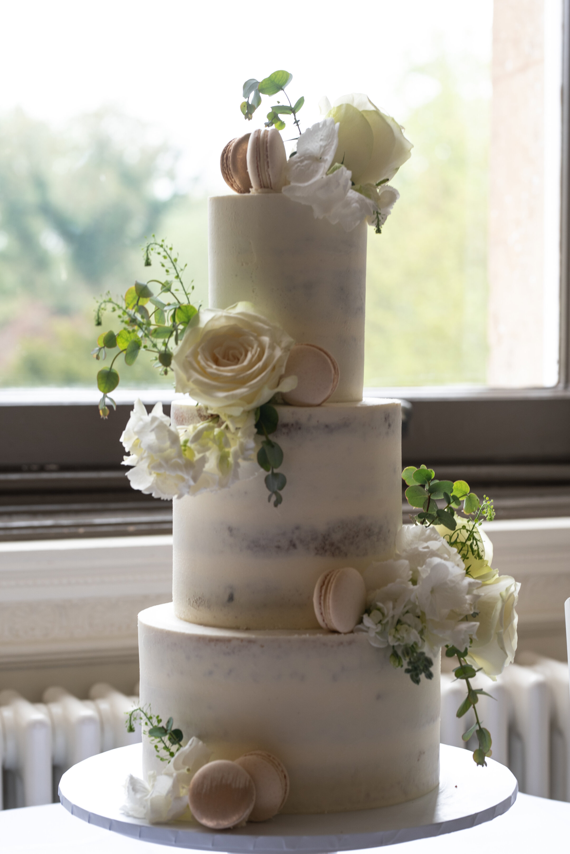 Three tier wedding cake with matching macaroons and flowers
