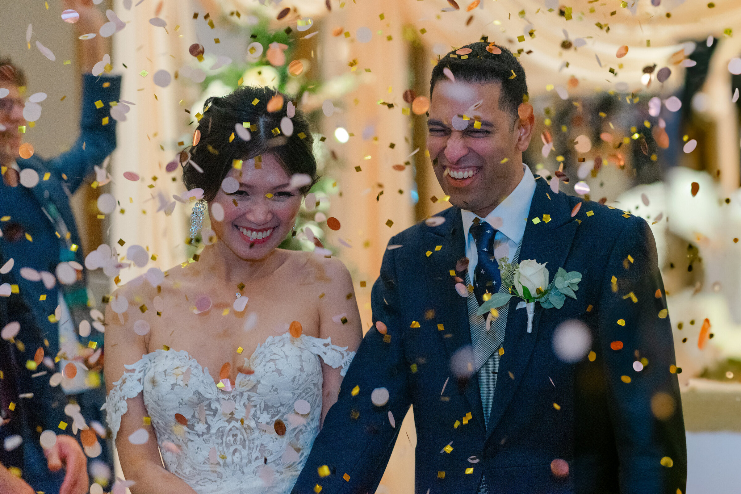 A multicultural couple smiling under a confetti shower at their Kimpton Fitzroy wedding in London, captured by Chi Ramos Photography.
