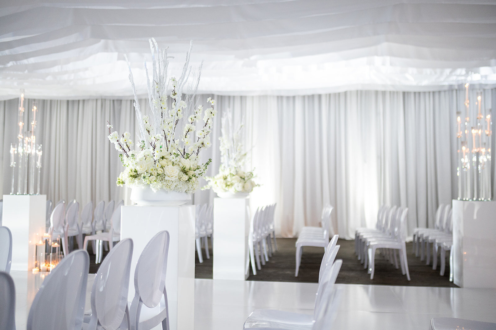 Modern white wedding ceremony at The Kent in Memphis, TN featuring floral arch, acrylic chairs, ambient candlelight, and luxury event design by Wells Design Co