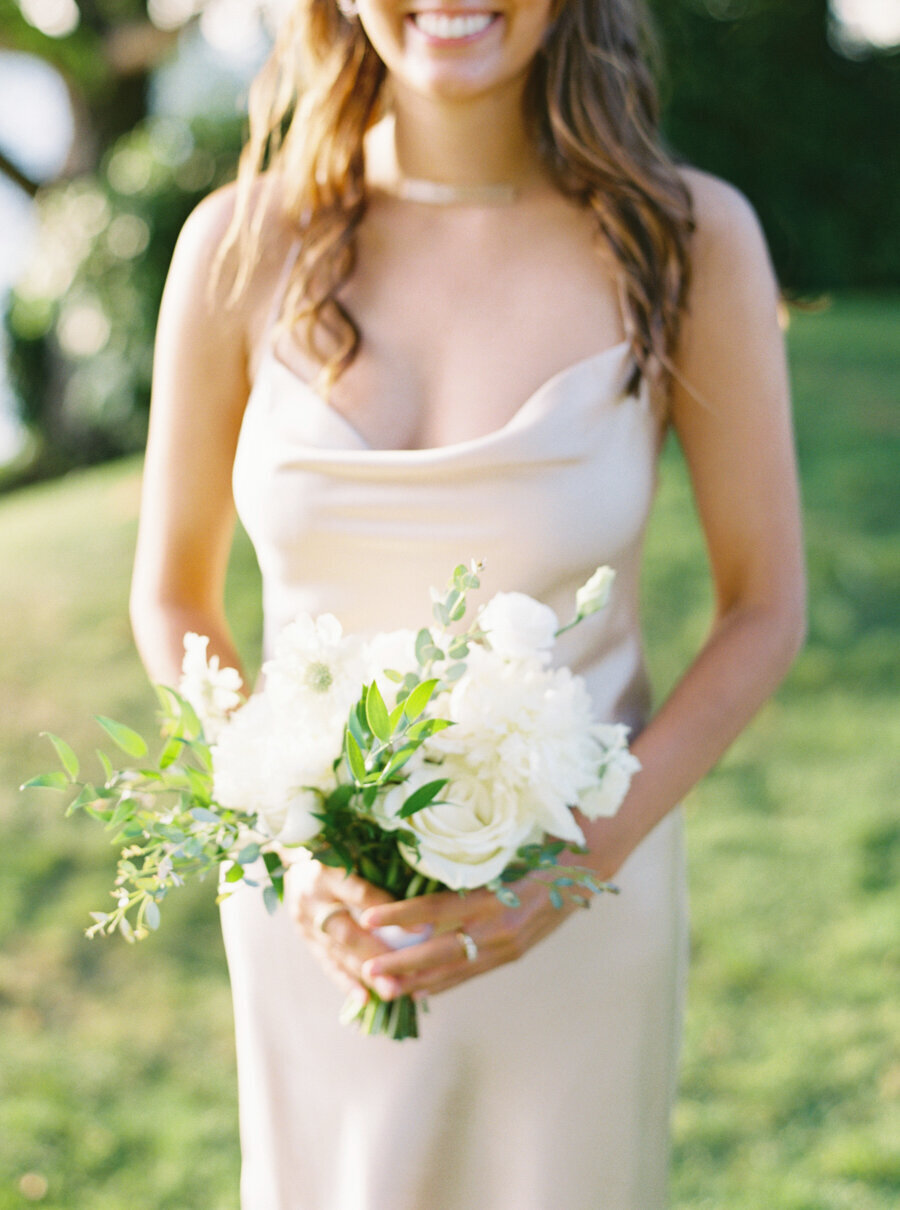 bridesmaid in gold satin dress holding white and green bouquet