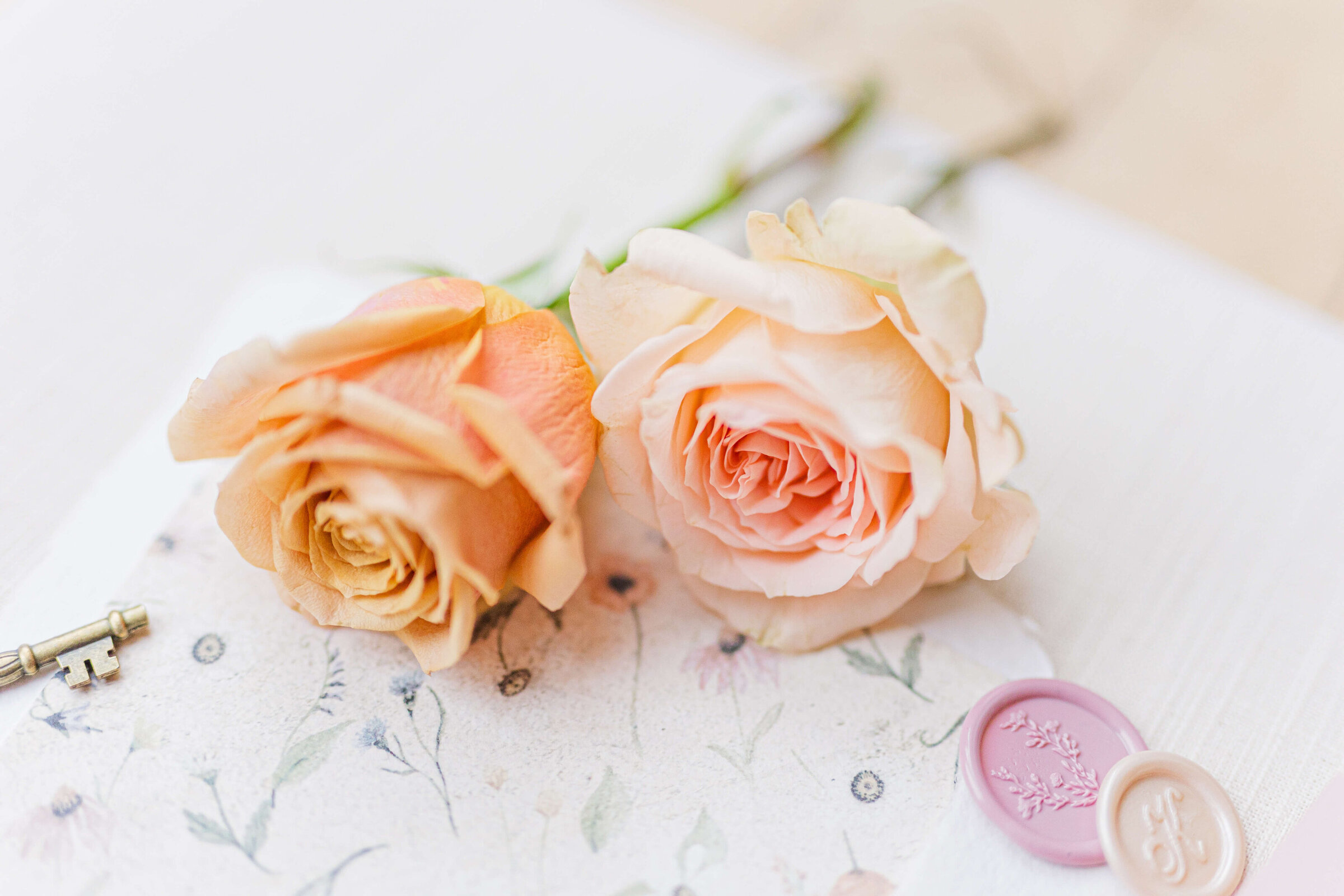 A photo of of two roses, one peach and one pink and two  rubber stamps