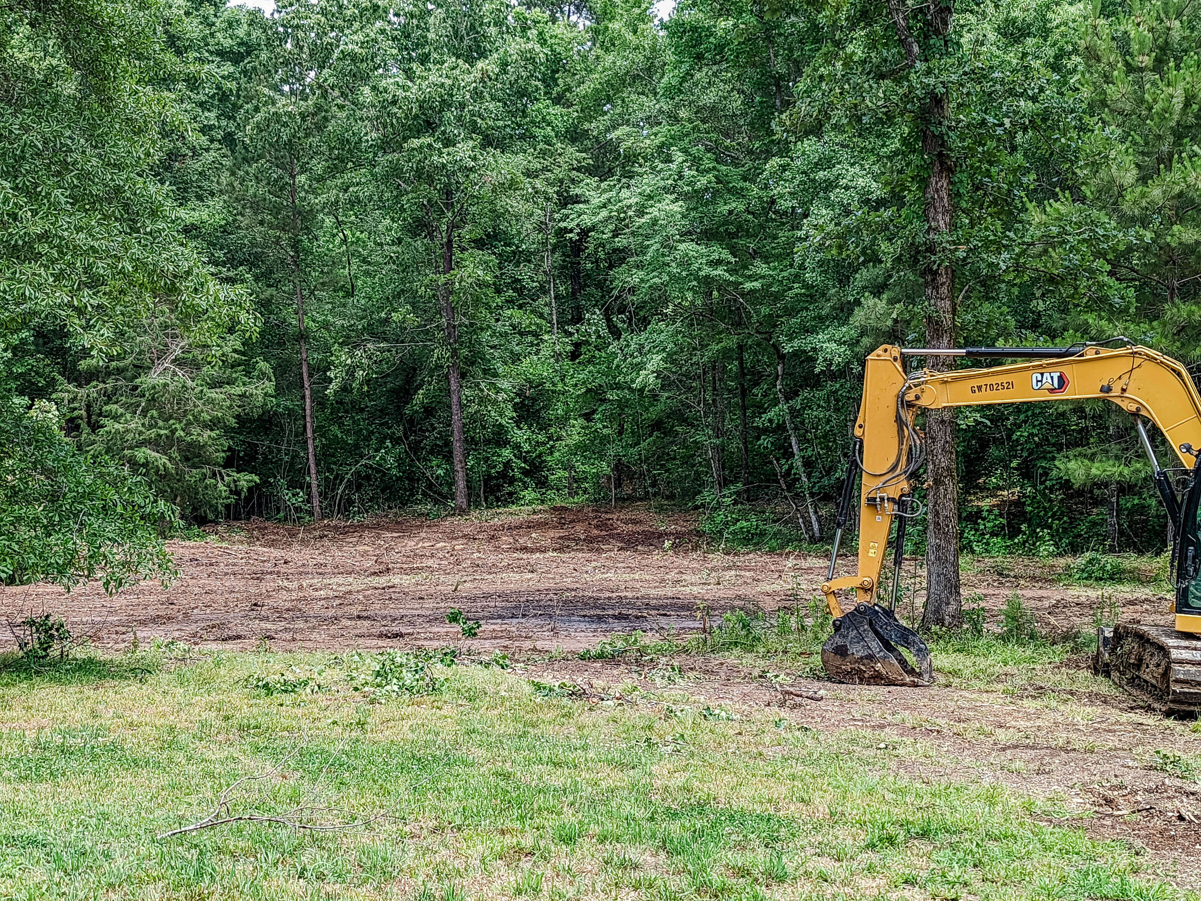 excavator-digging-up-brush-on-property-treeline