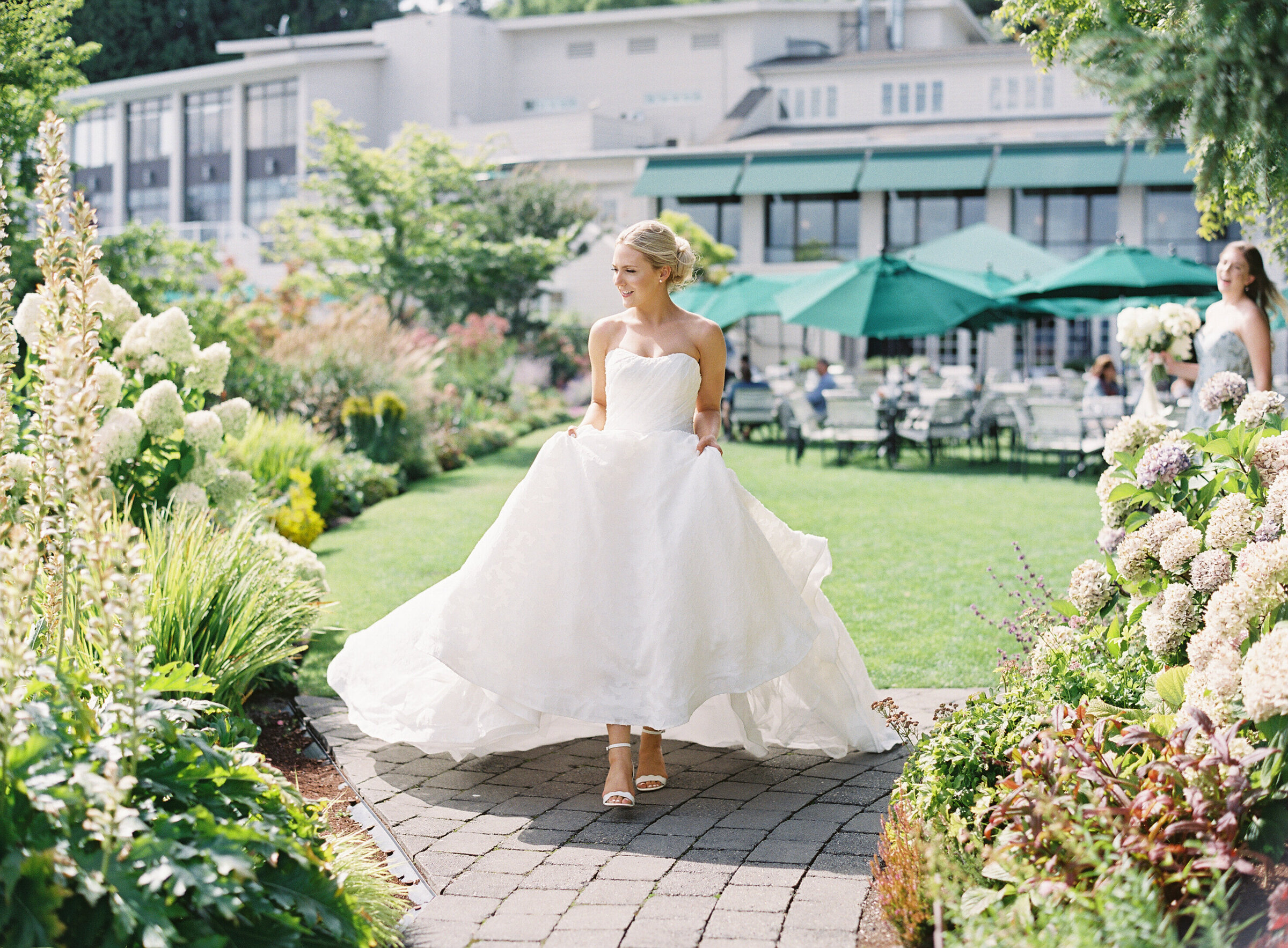 bride holding her dress and walking on grass on sunny day