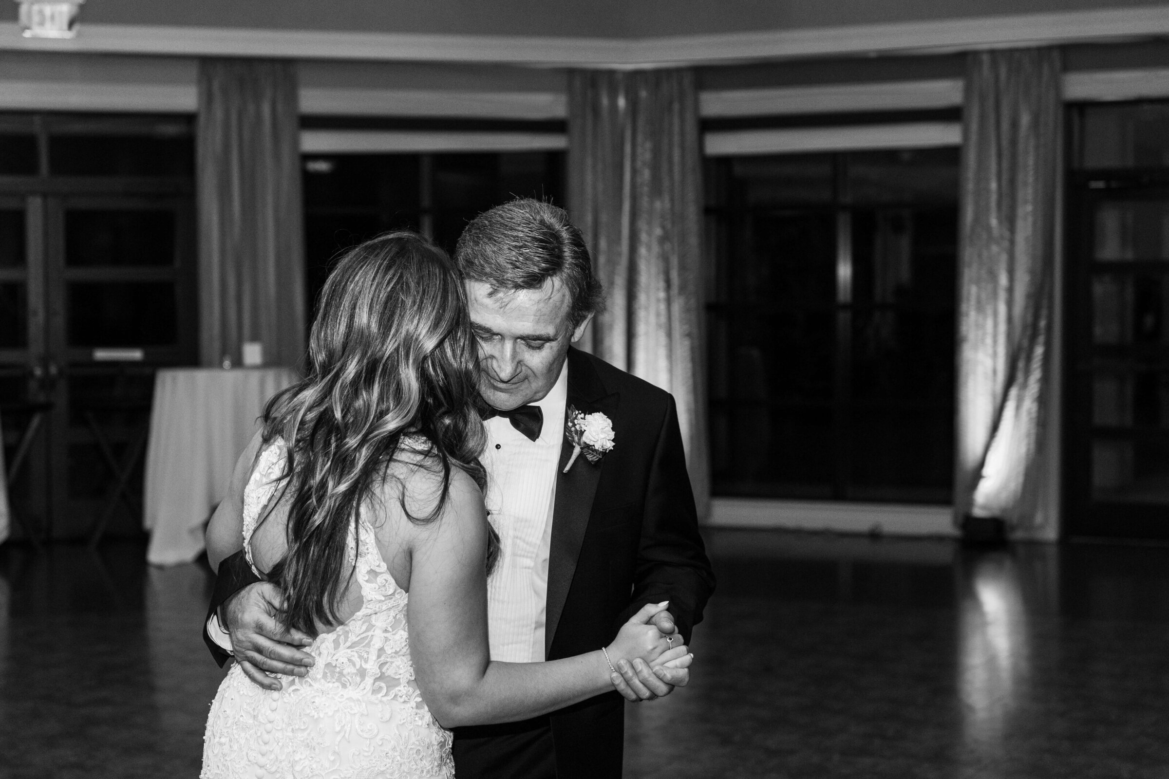 A black and white picture of a bride and her dad dancing on her wedding day.