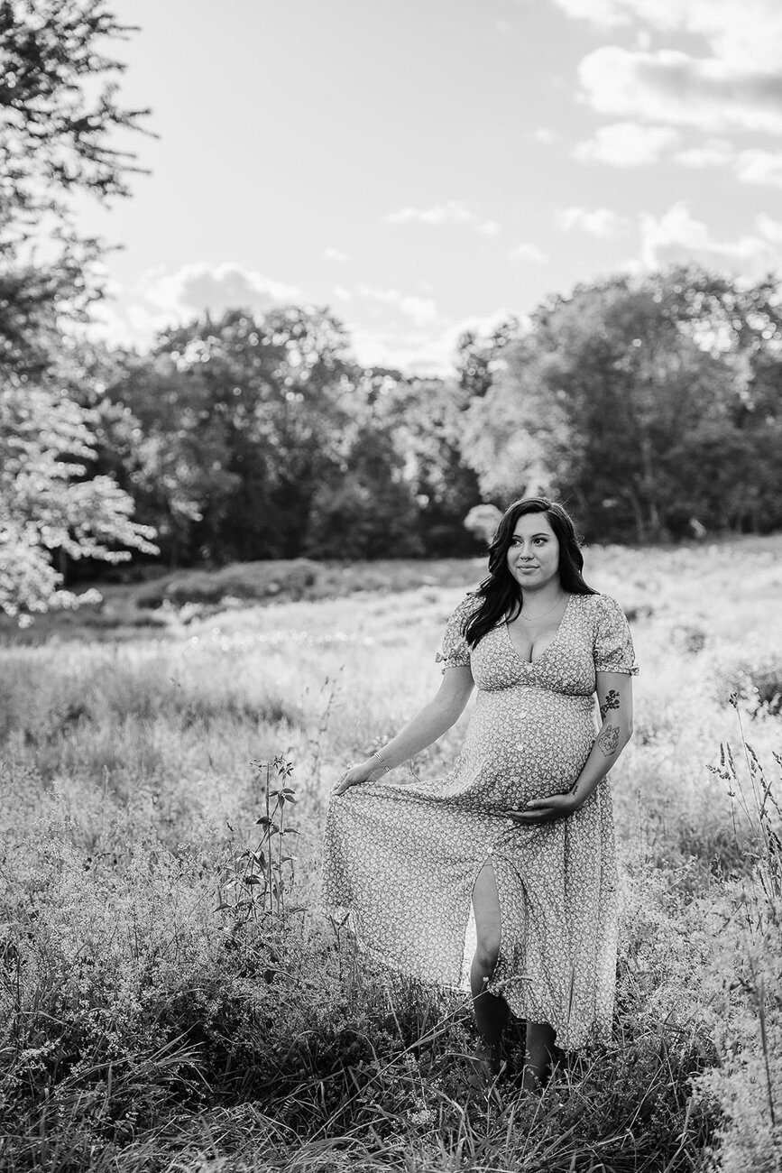 black and white image of pregnant woman walking through field