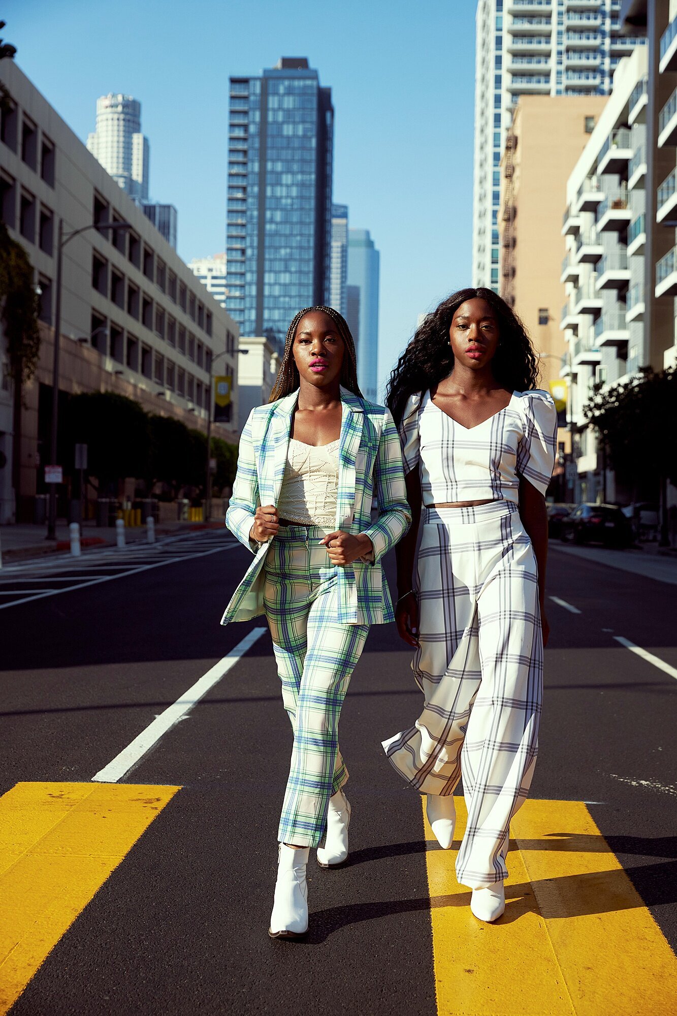 Urban Los Angeles senior portraits of two stylish teen girls in plaid suits walking downtown streets, editorial fashion photoshoot