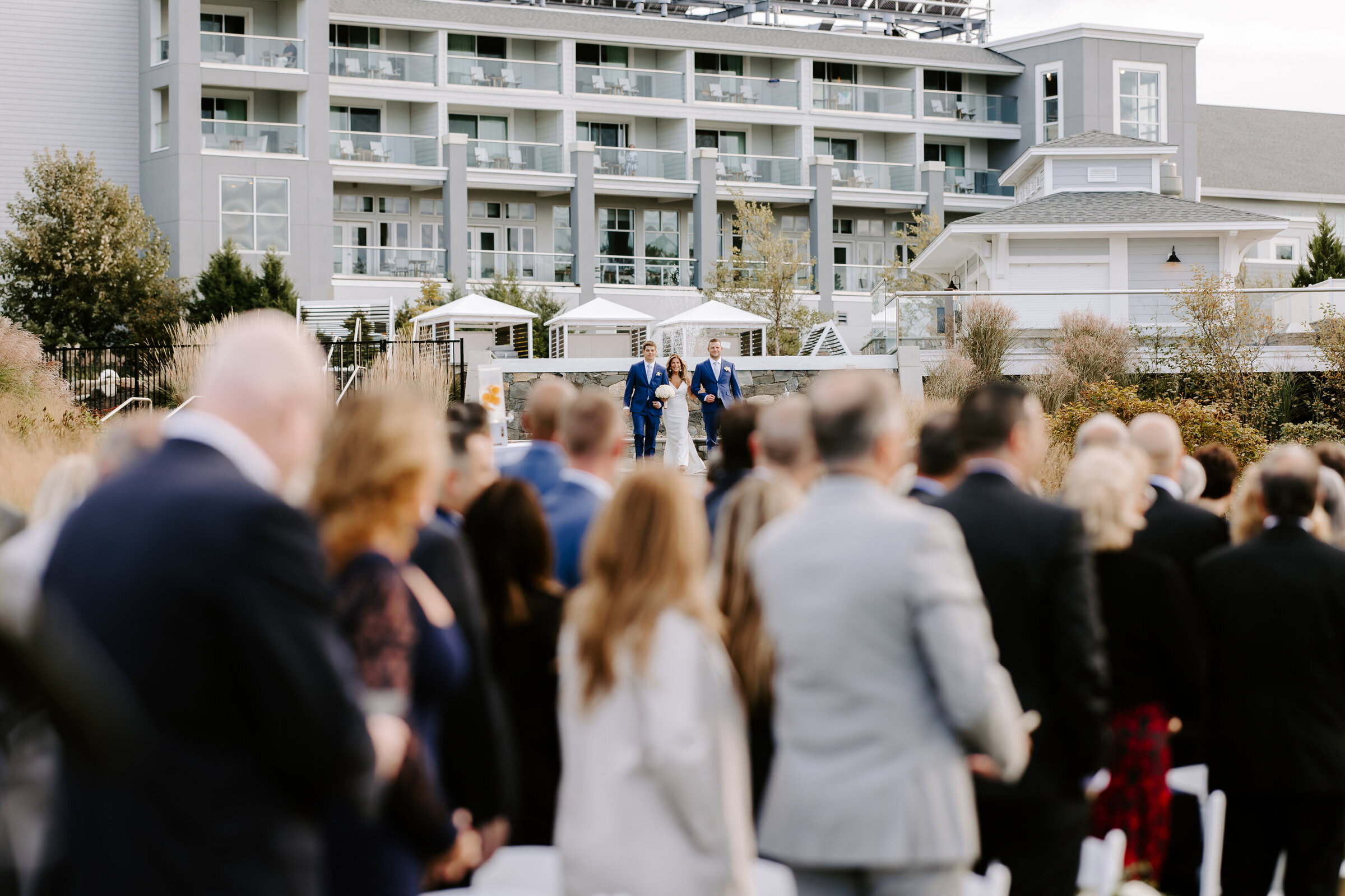 Guests turn and look at bride as her sons walk her down the aisle at The Cliffhouse in maine