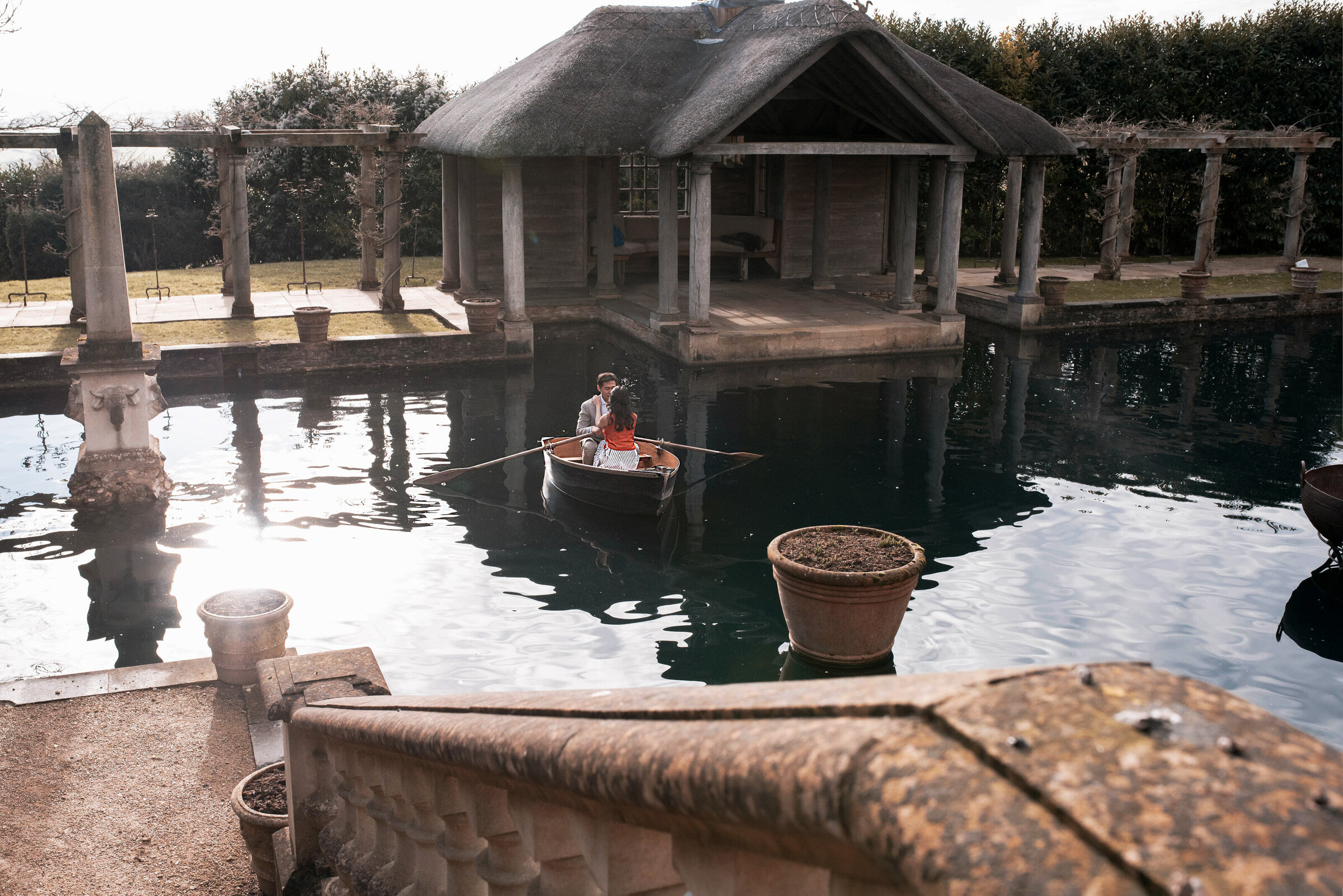 Man and woman on a small rowing boat in the middle of the pond at Euridge Manor wedding venue