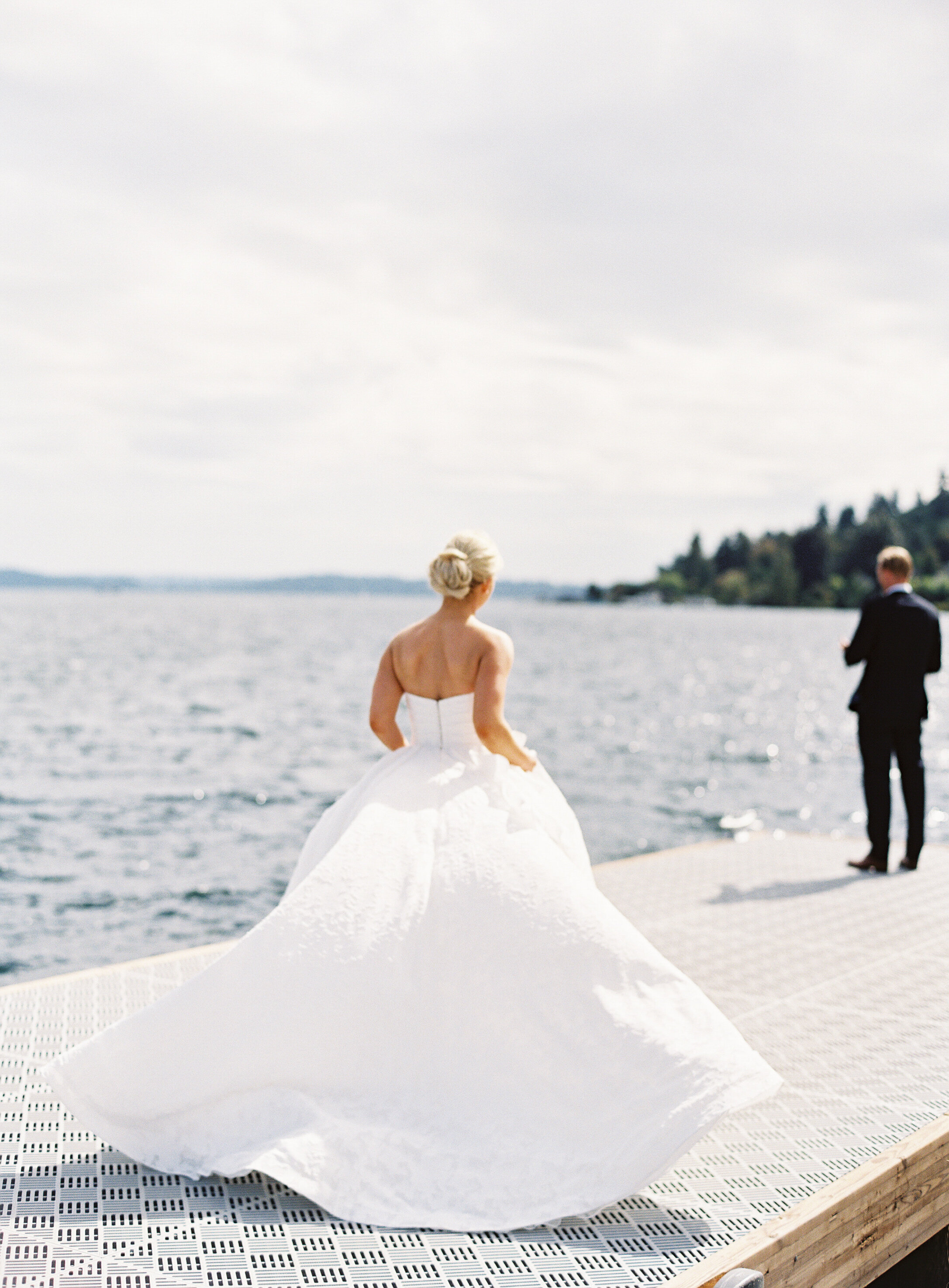 bride walks in wind on dock towards her groom for first look