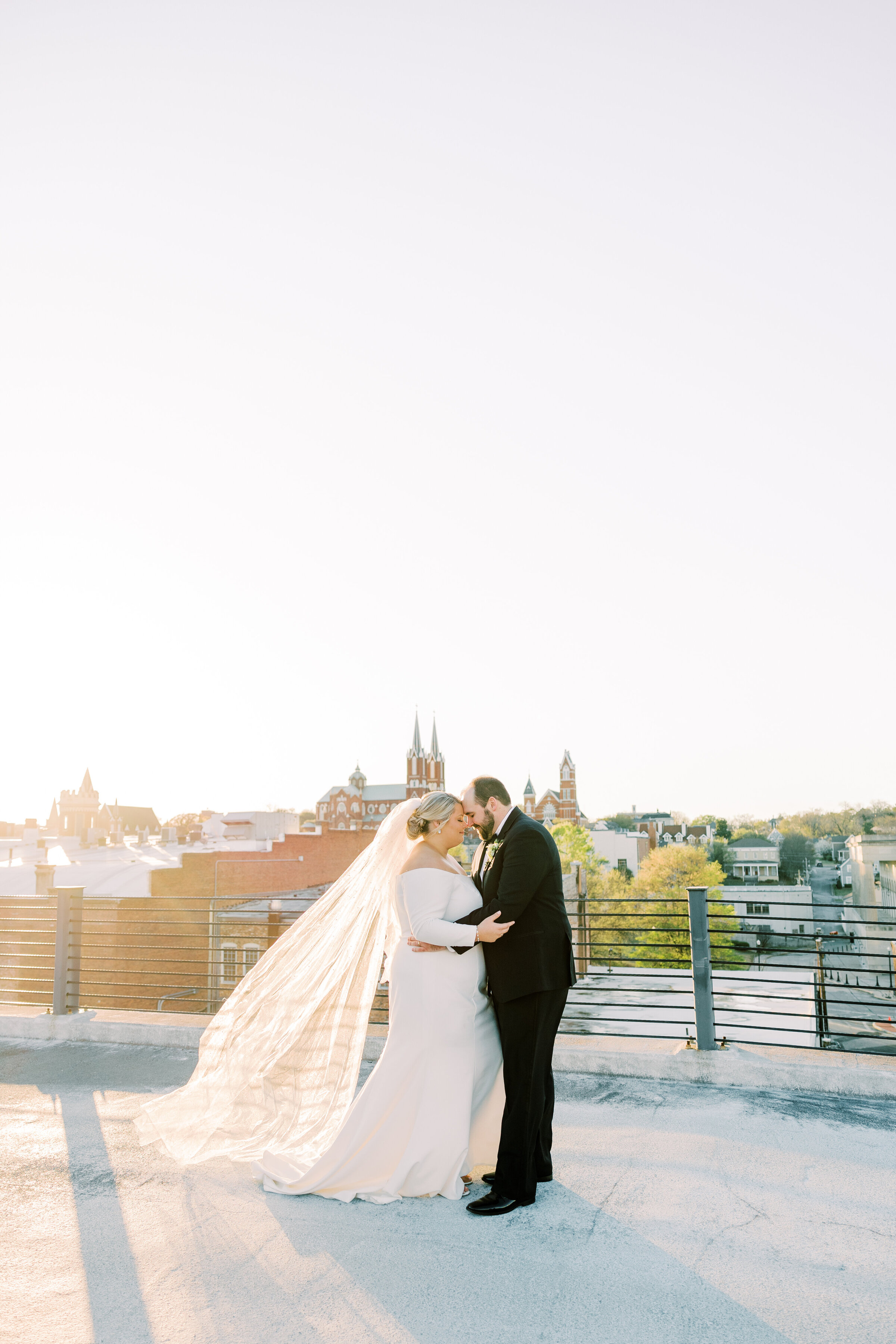 Bride and groom embracing outside with skyline behind
