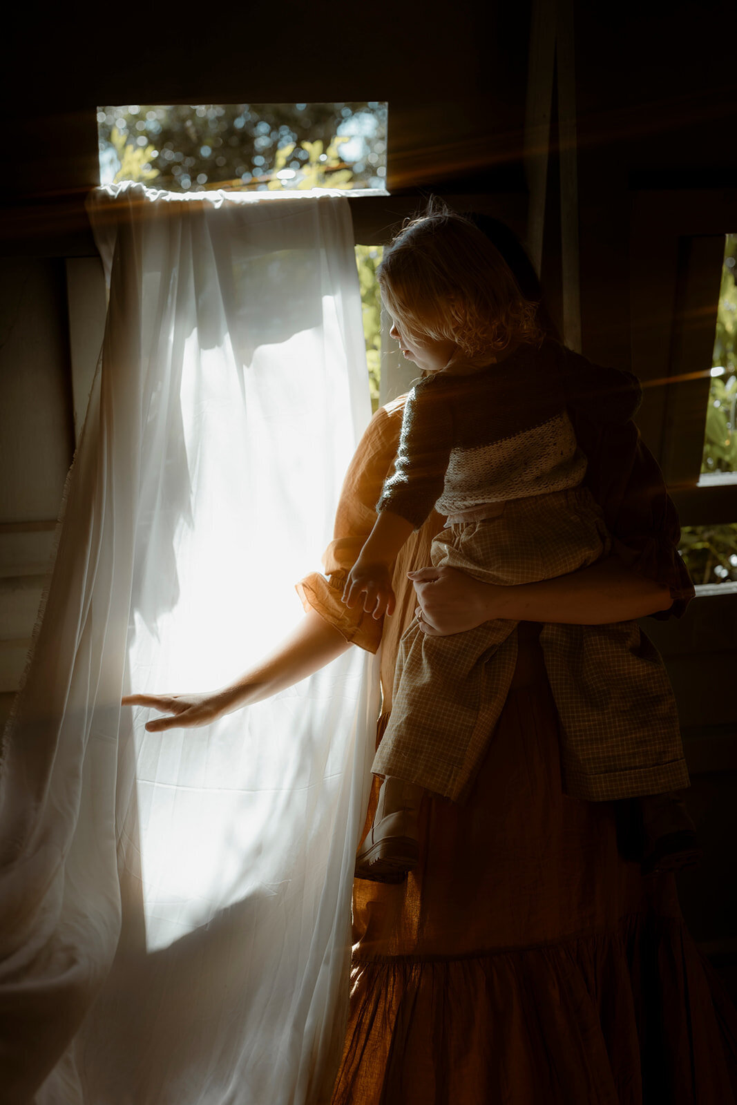 photo of mother holding back the curtain with her son