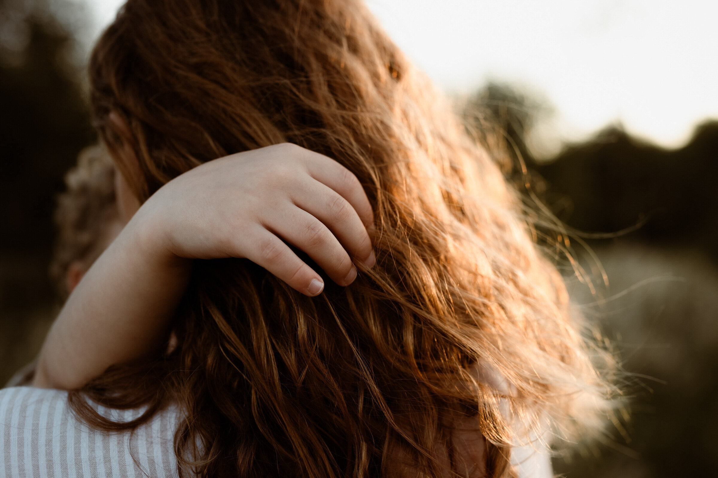 beautiful close up image of a boy's hand caressing his mother's hair