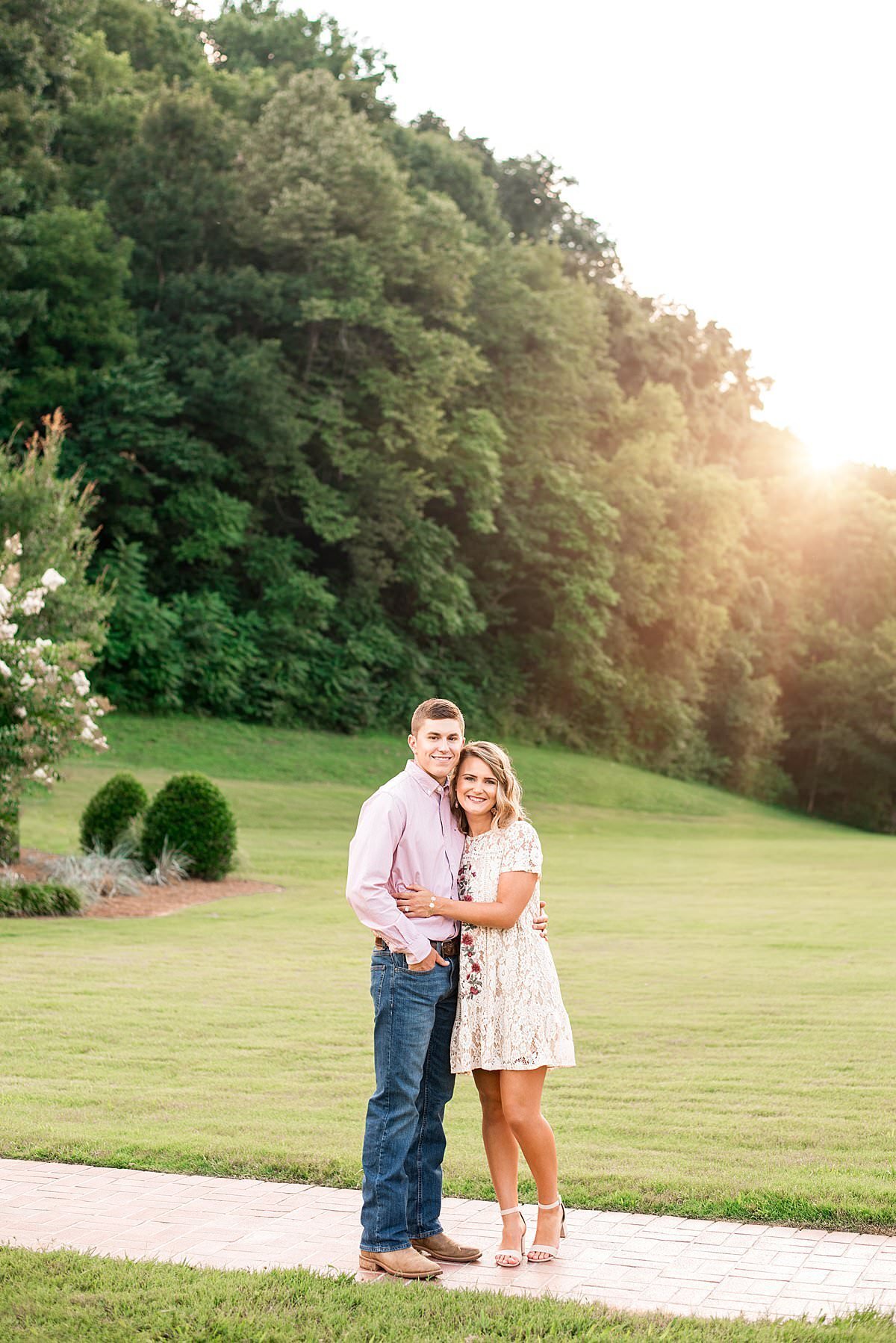 Couple standing together on cobblestone pathway with sunsetting over ridge at golden hour