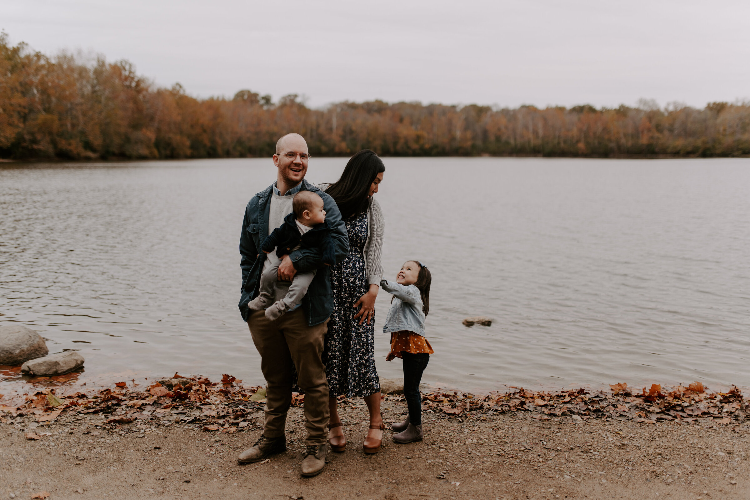 A family of four poses laughing on a lakeshore at the Indianapolis Museum of Art.