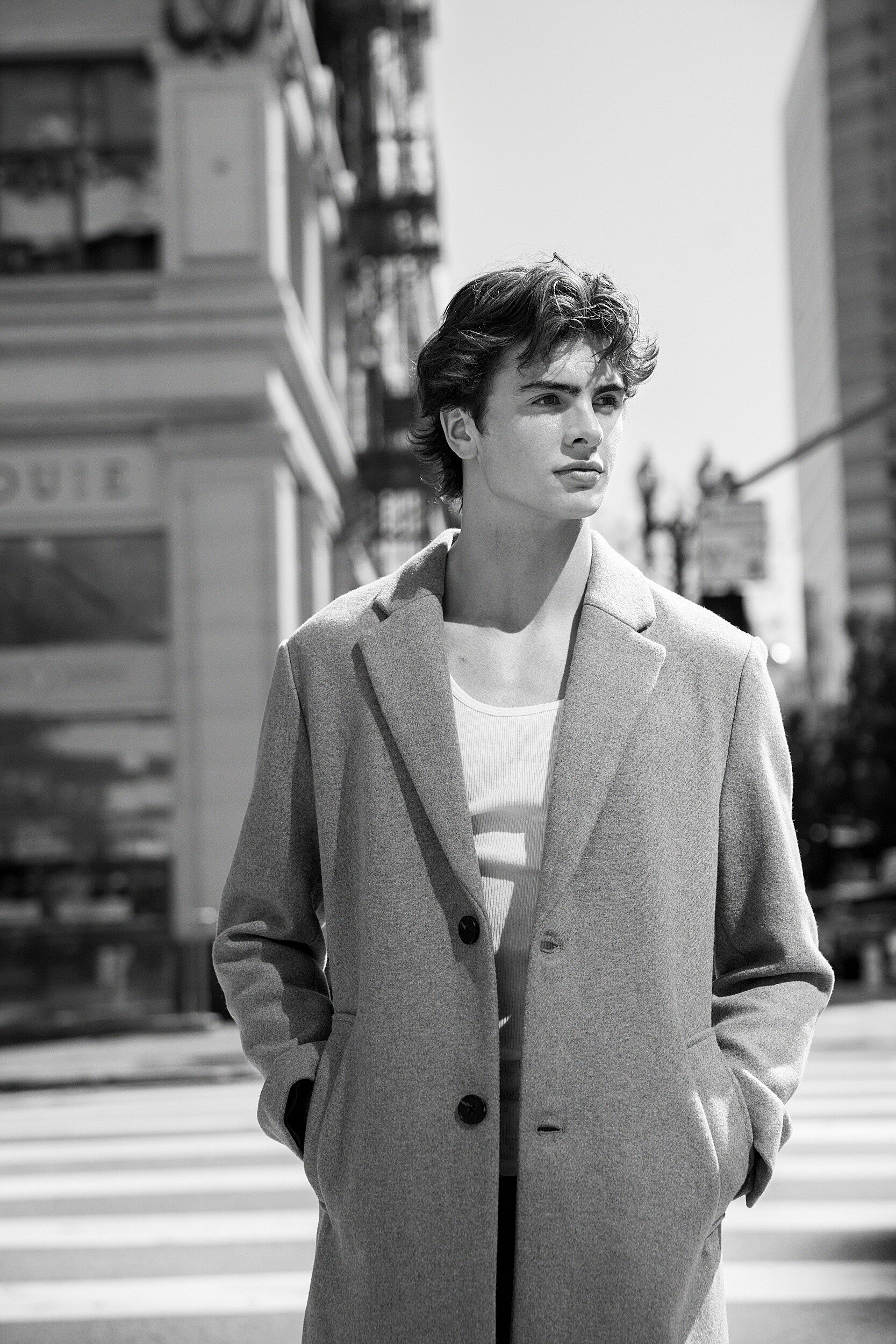 Editorial Los Angeles senior portrait of teenage boy in black and white, wearing long coat in downtown city streets