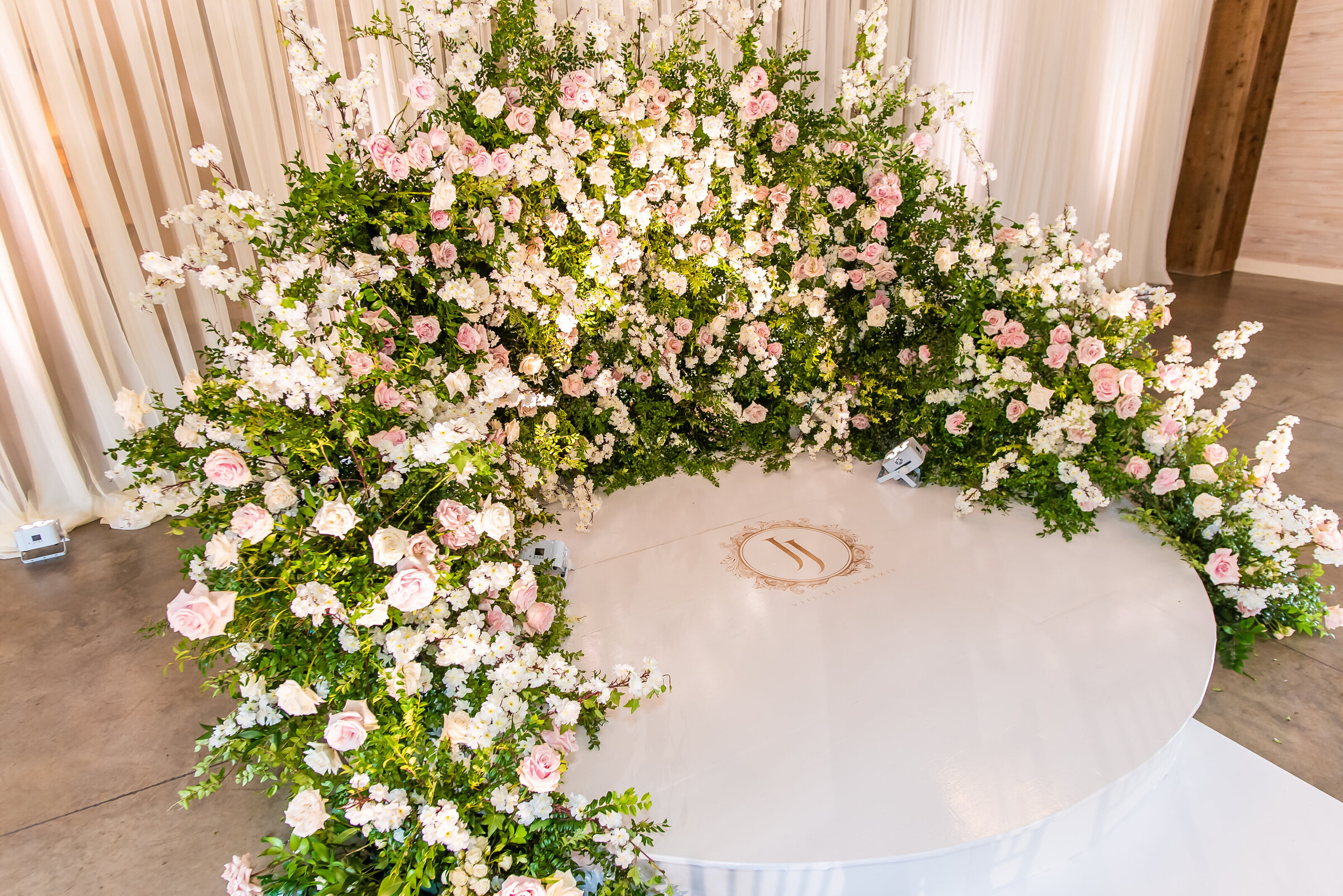 Custom circular stage wrapped in fresh pink and white florals with monogrammed floor design at a high-end Birmingham wedding by Wells Design Co.