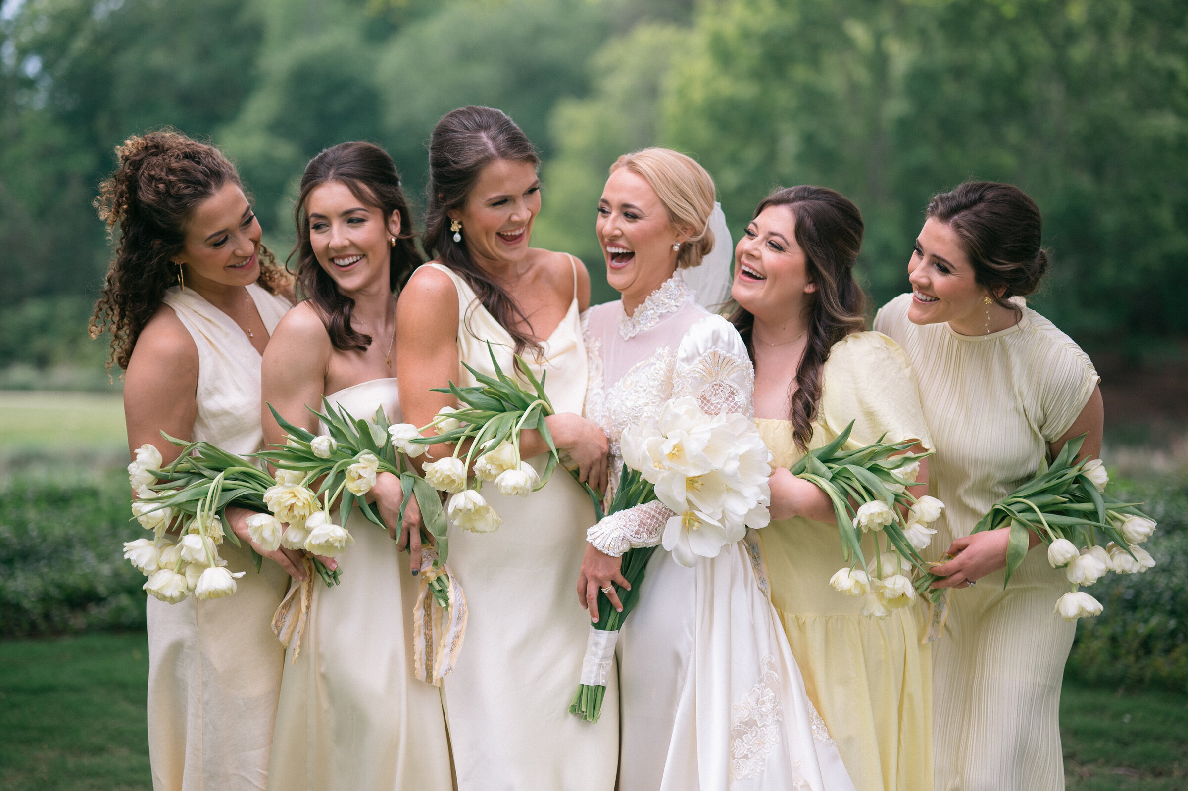 women hugging and smiling each other in dresses holding tulips