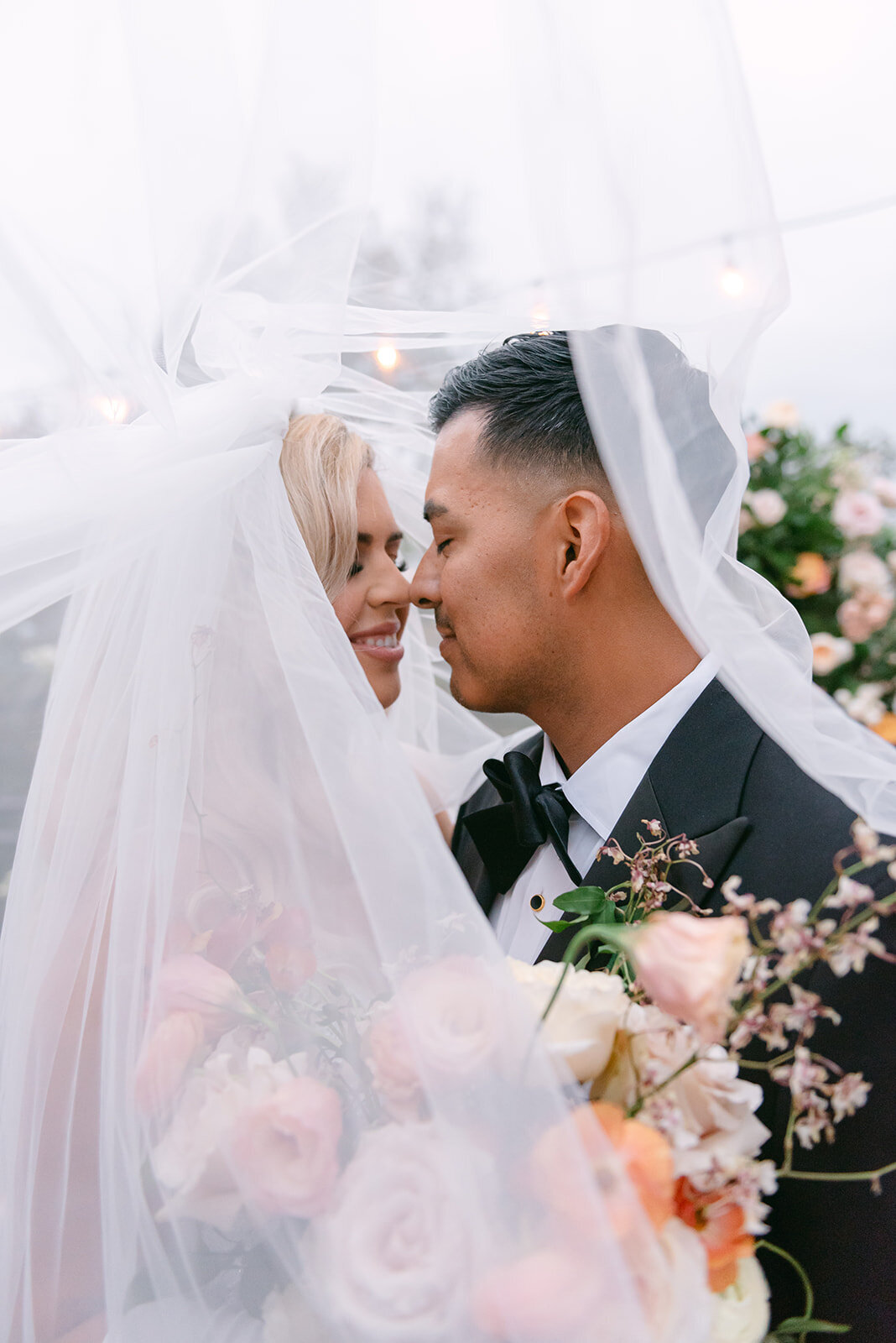 Bride and groom sharing an intimate veil-covered kiss at a mansion wedding in Austin, Texas, with soft pastel florals and romantic natural light