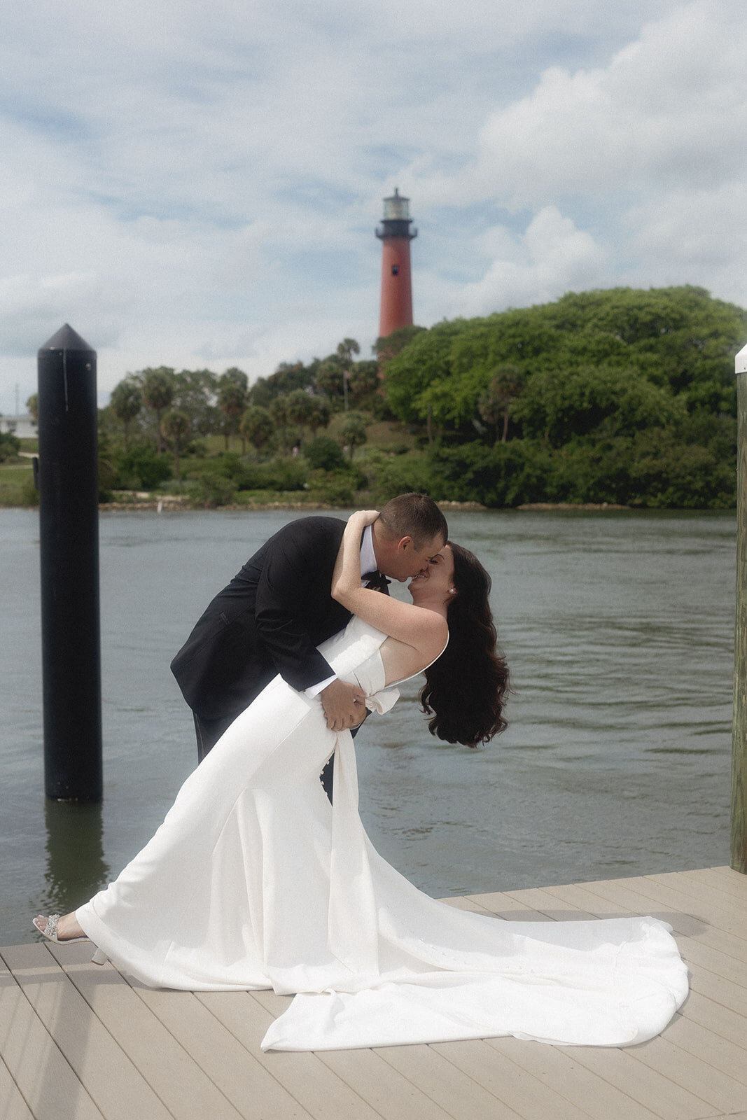 Bride and groom kissing with lake and lighthouse in the background