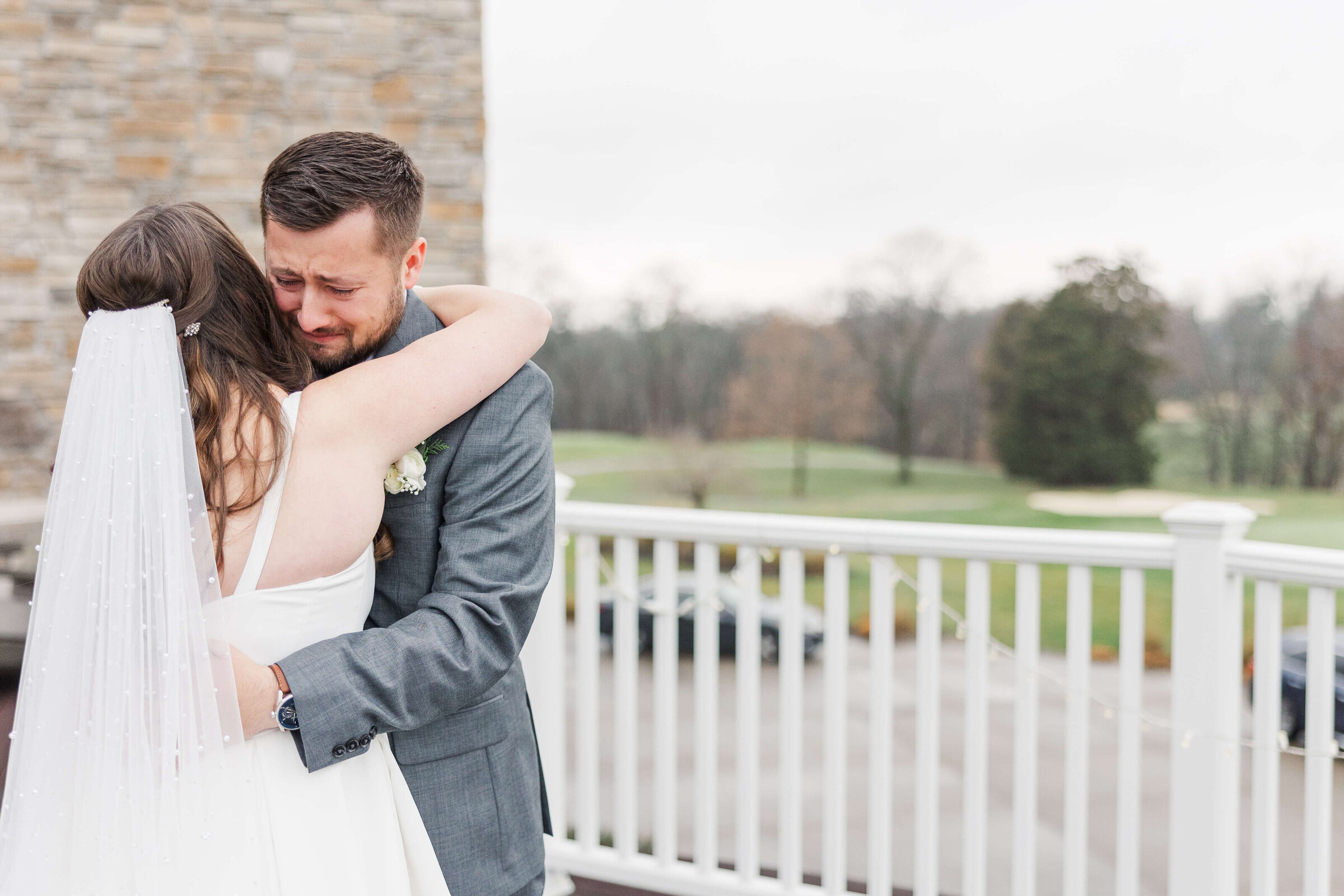 A groom who just saw his bride is crying as he hugs on her a winter day at Cooper Creek Event Center in Cincinnati Ohio