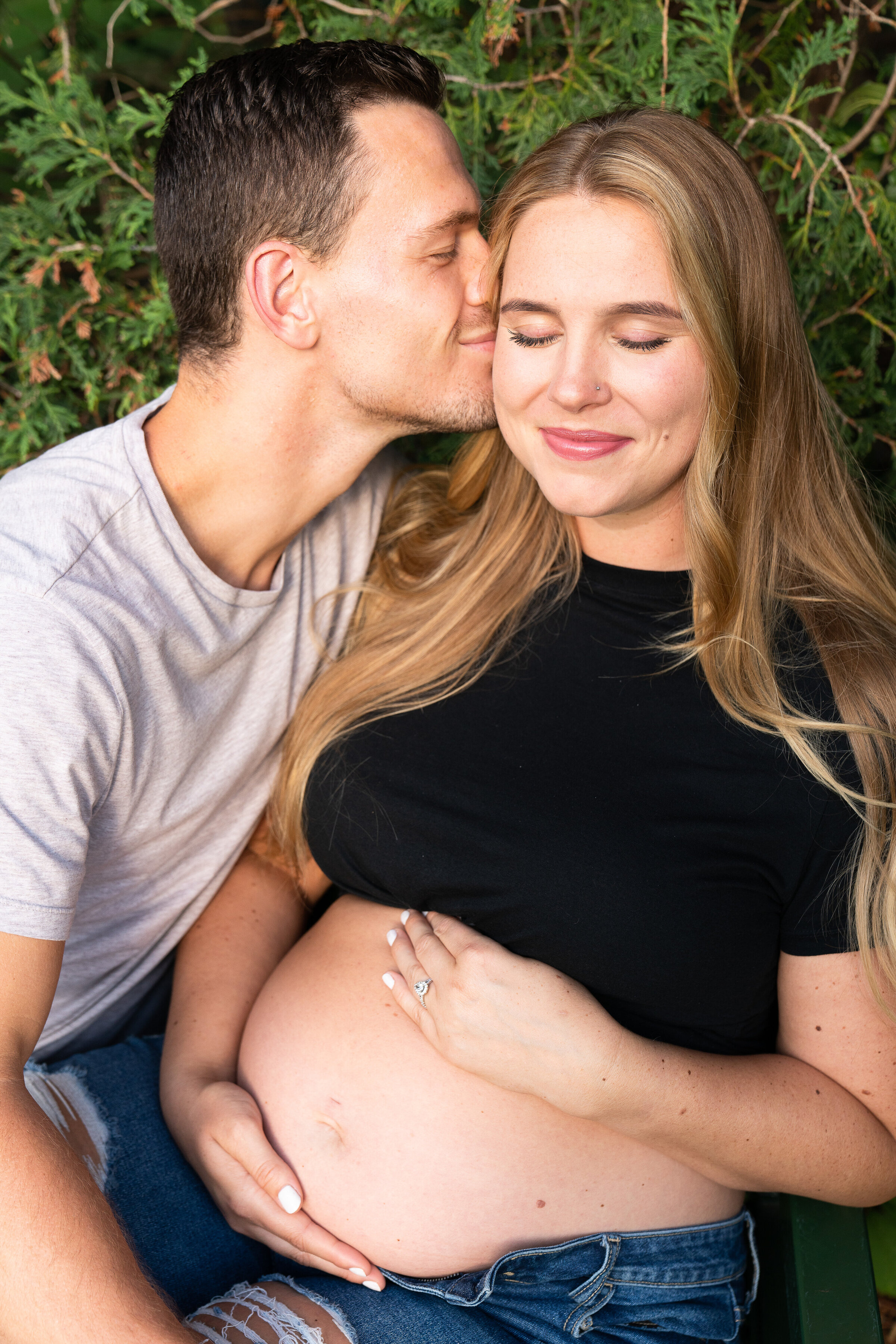 Man kisses pregnant wife during their maternity photo shoot at Arneson Acres Park in Edina, Minnesota