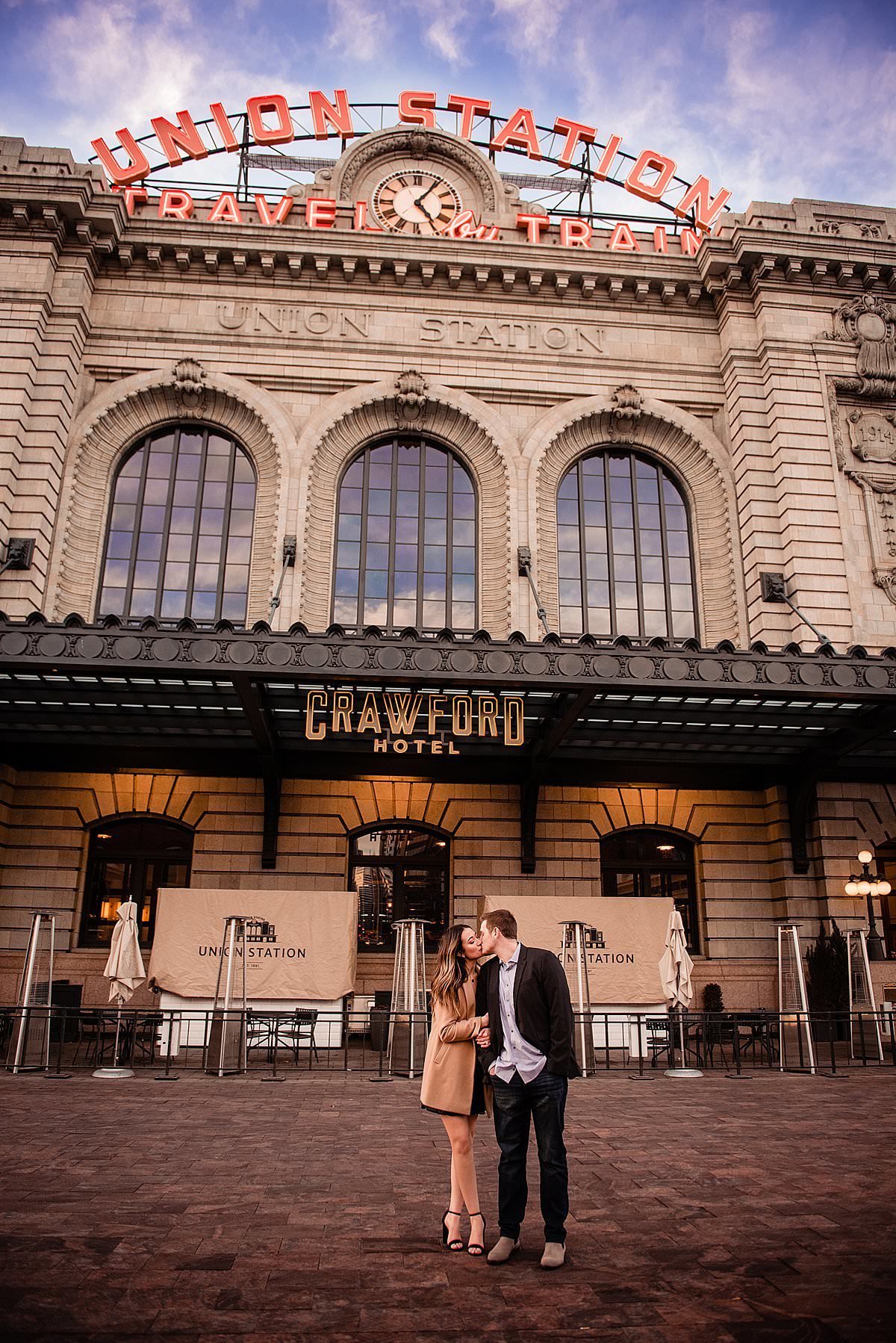 Dramatic photo outside of Union Station Denver of couple snuggled together and sharing a kiss